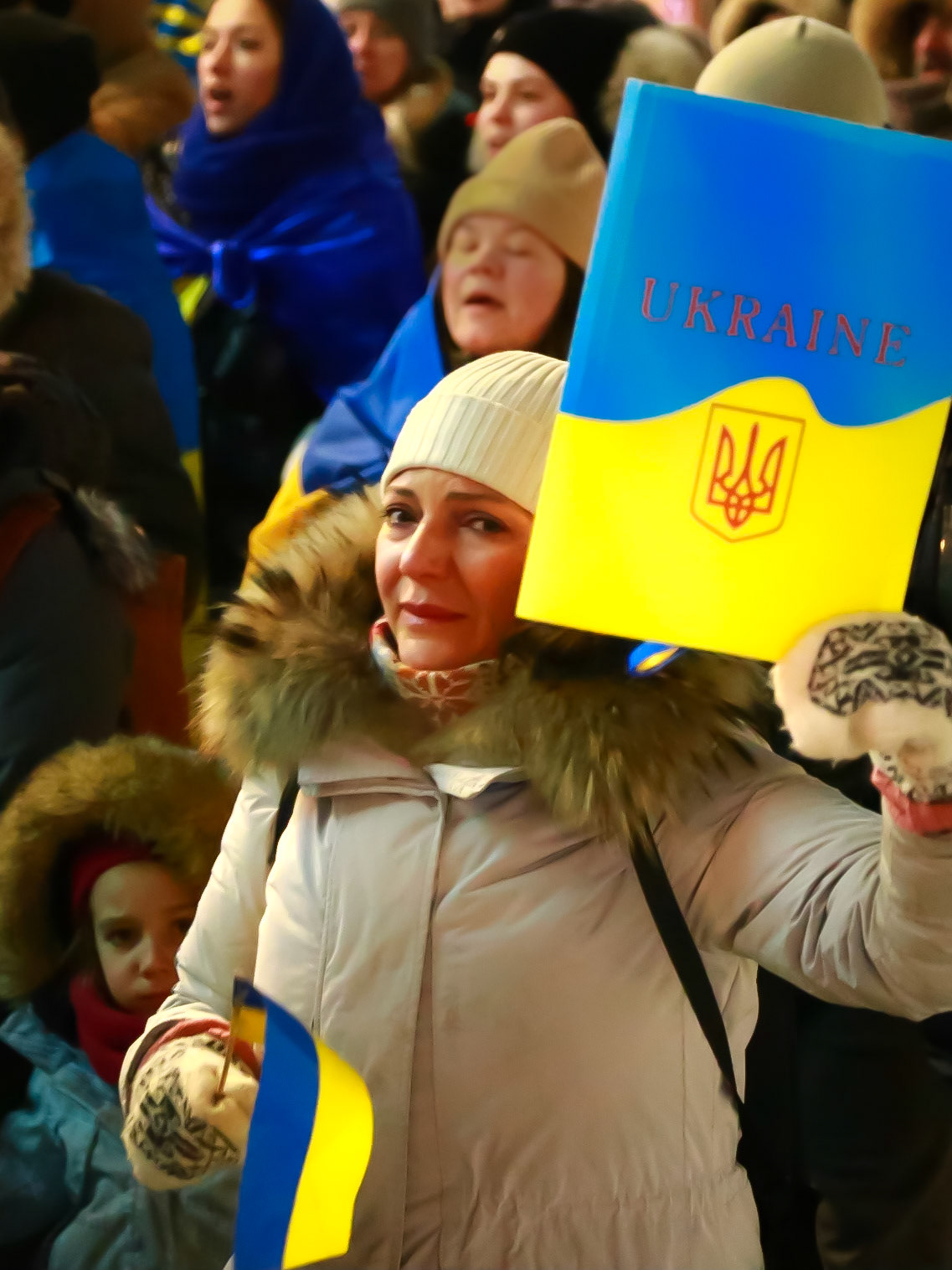 Étreinte par l'émotion, une femme tend devant l'objectif les couleurs de l'Ukraine