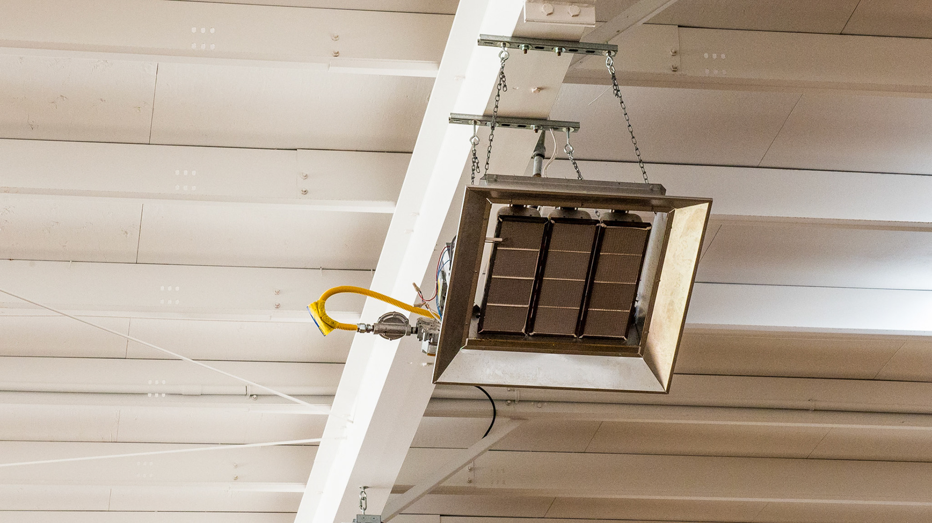Gas powered radiant heaters suspended from the ceiling of an indoor arena.