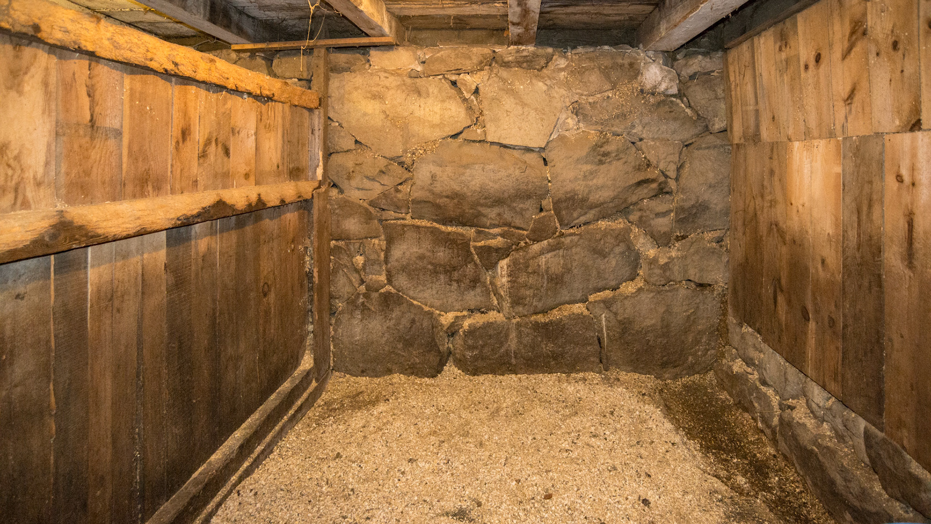 Barns built into the side of a hill often have their back wall made of stone like this one in Massachusetts.  The right side wall also has a stone foundation.  The left side wall has a large wood beam laid across the floor with vertical tongue and groove boards.