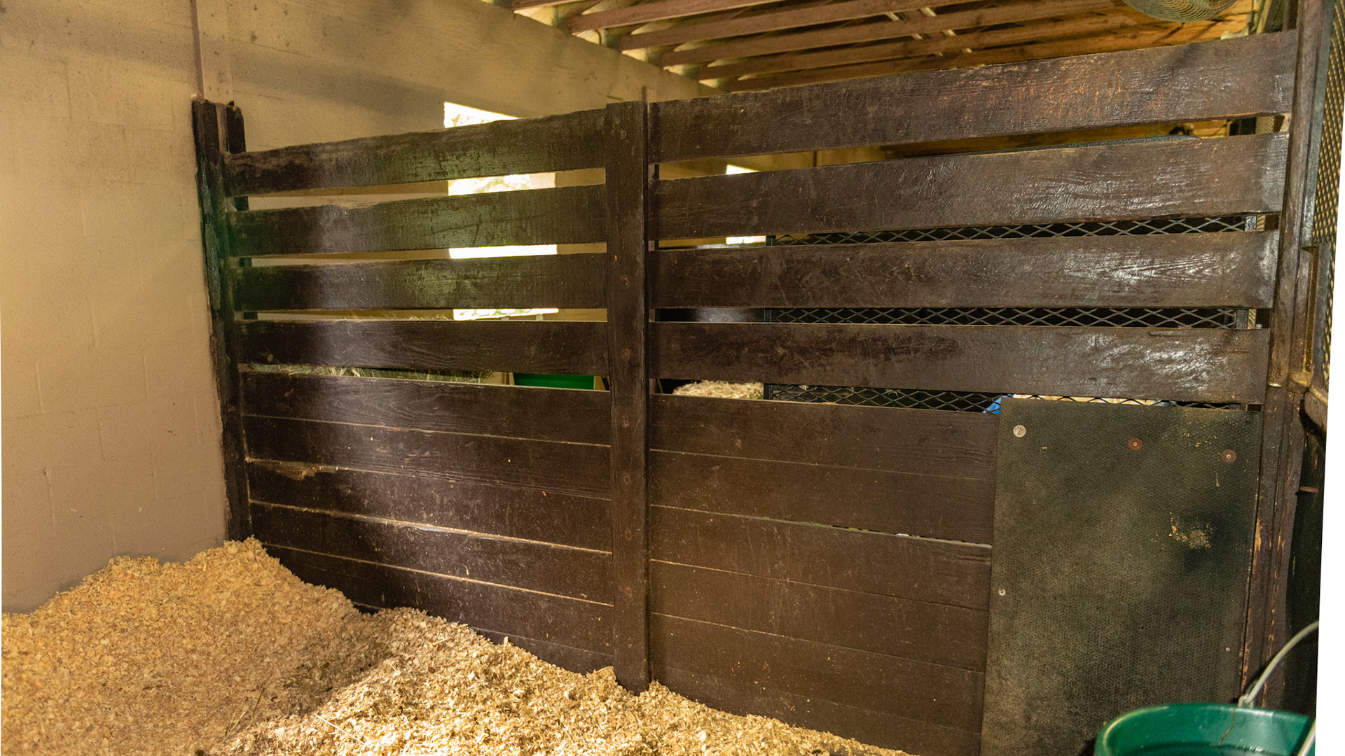 Stall wall with a sandwich board and the upper boards separated for ventilation.  Carriage bolt heads do not need recessing