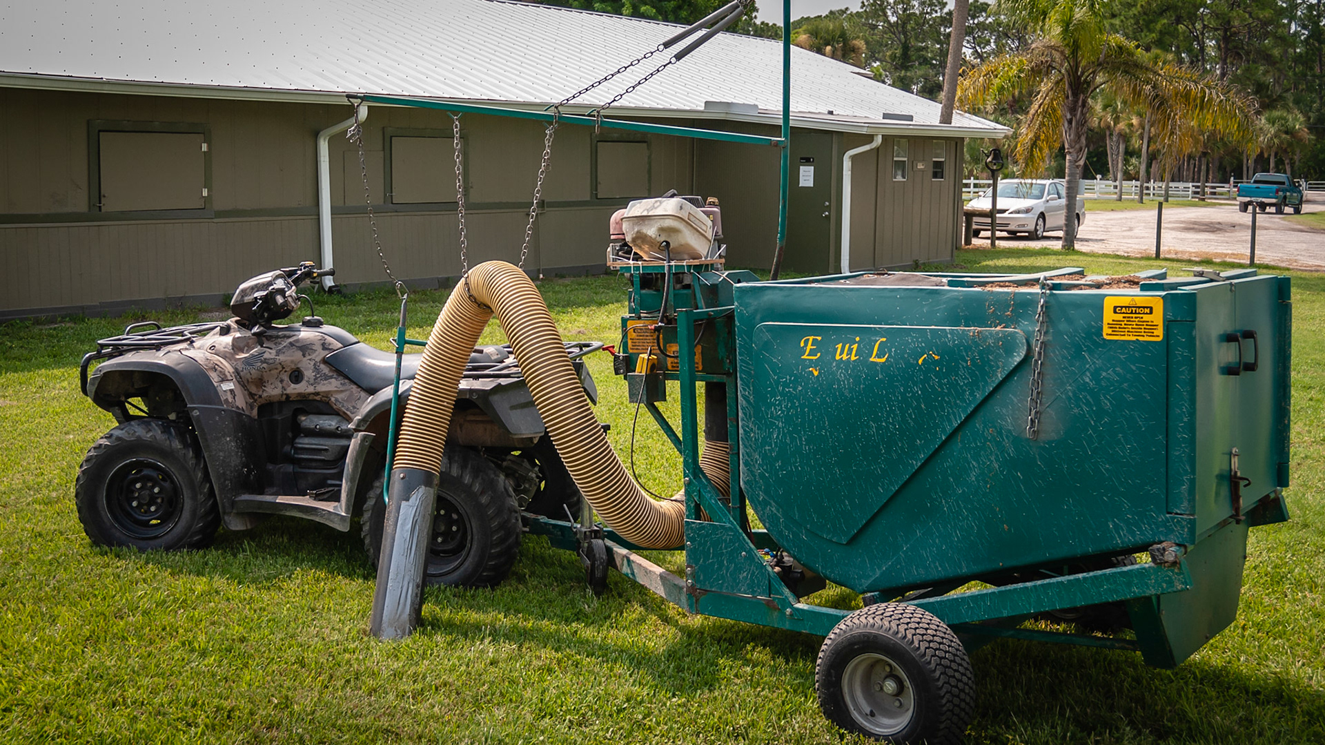 The Equi-Lynx manure vacuum pulled by an ATV. Note the arm and chain system to support the hose.
