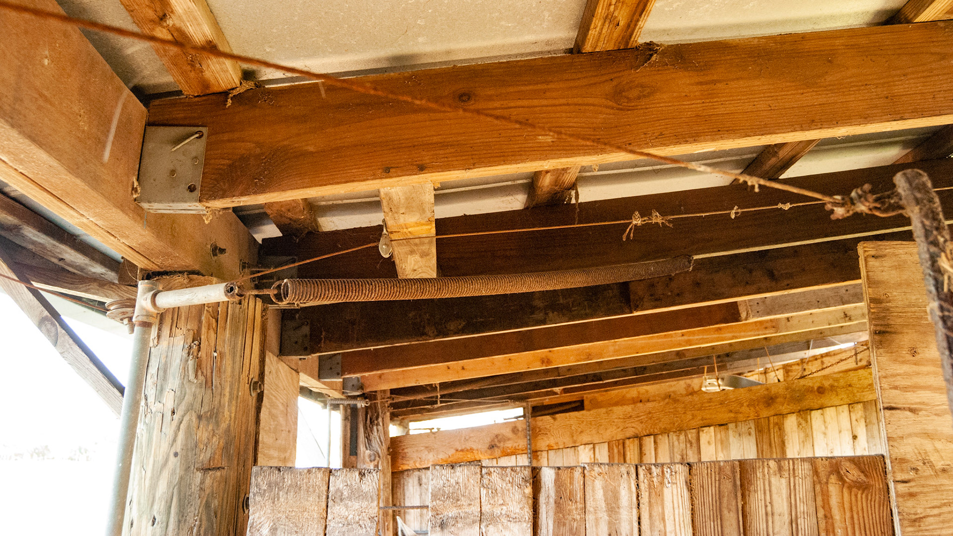This is part of a complex arrangement of cables, pulleys, levers and springs that allowed someone on the front side of the stall to open or close the back door of the stall.