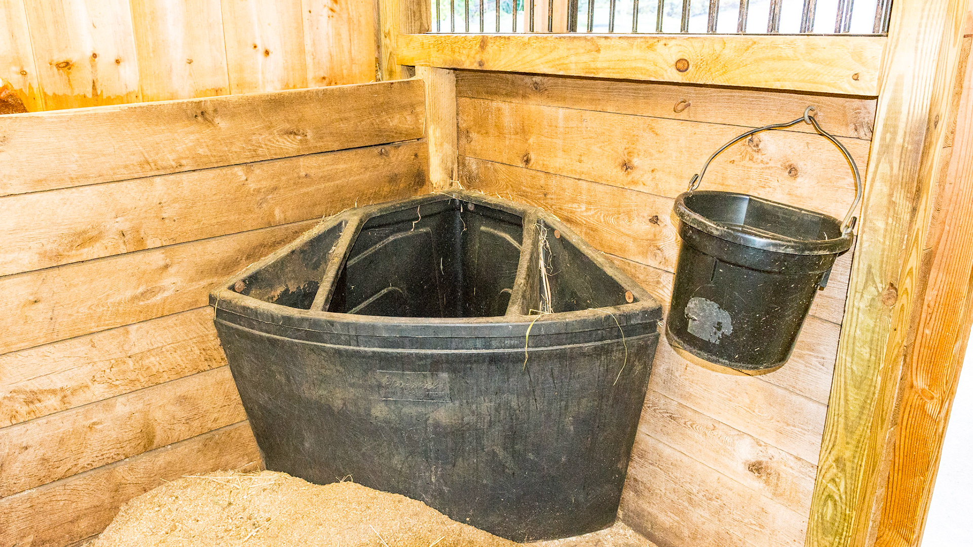 This plastic formed hay and feed tub keeps the hay contained and not scattered over the floor. The water is hung nearby. While this has an appeal of efficiency, I see three problems. 1) the horse’s head needs to be deep inside the tub to finish eating. This may not work with a nervous or claustrophobic horse. 2) It limits the ventilation and forces the horse to eat with his nostrils inhaling the dust so many bales have.  3) They are impossible to clean well.