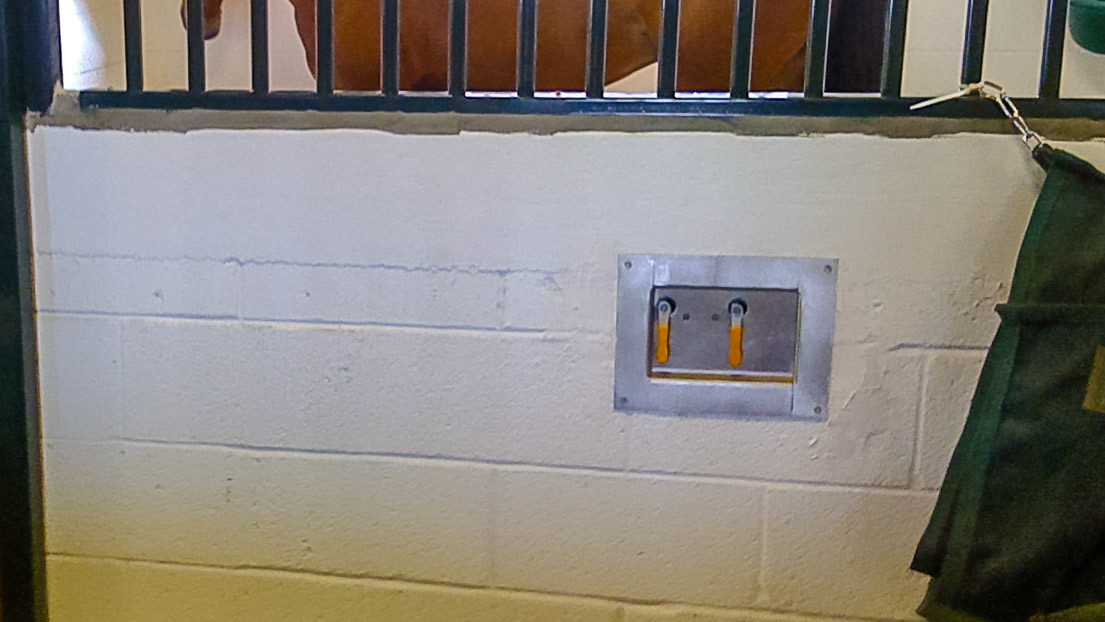 Recessed handles control water flow into individual buckets inside the stall.