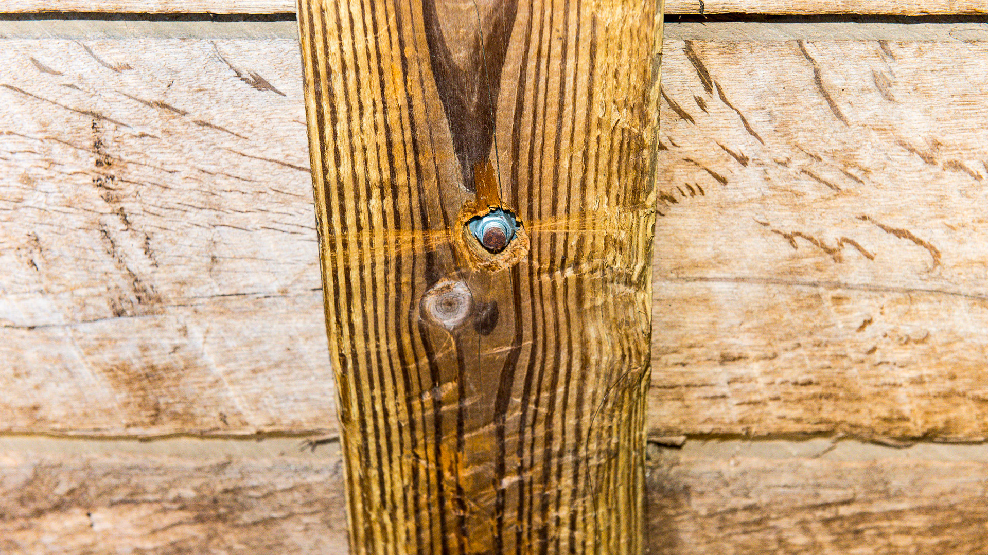 Details of the bolt shaft cut level with the board and the nut and washer counter-sunk into the wood.