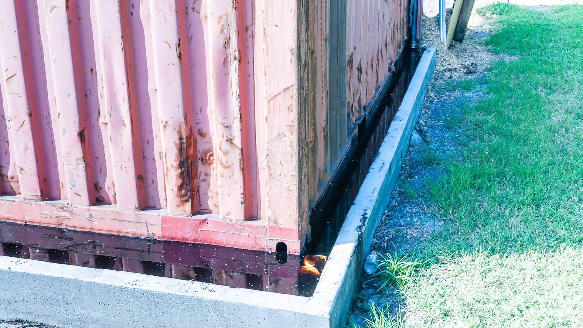 Container sets on a concrete floor with a water dam to contain leakage.