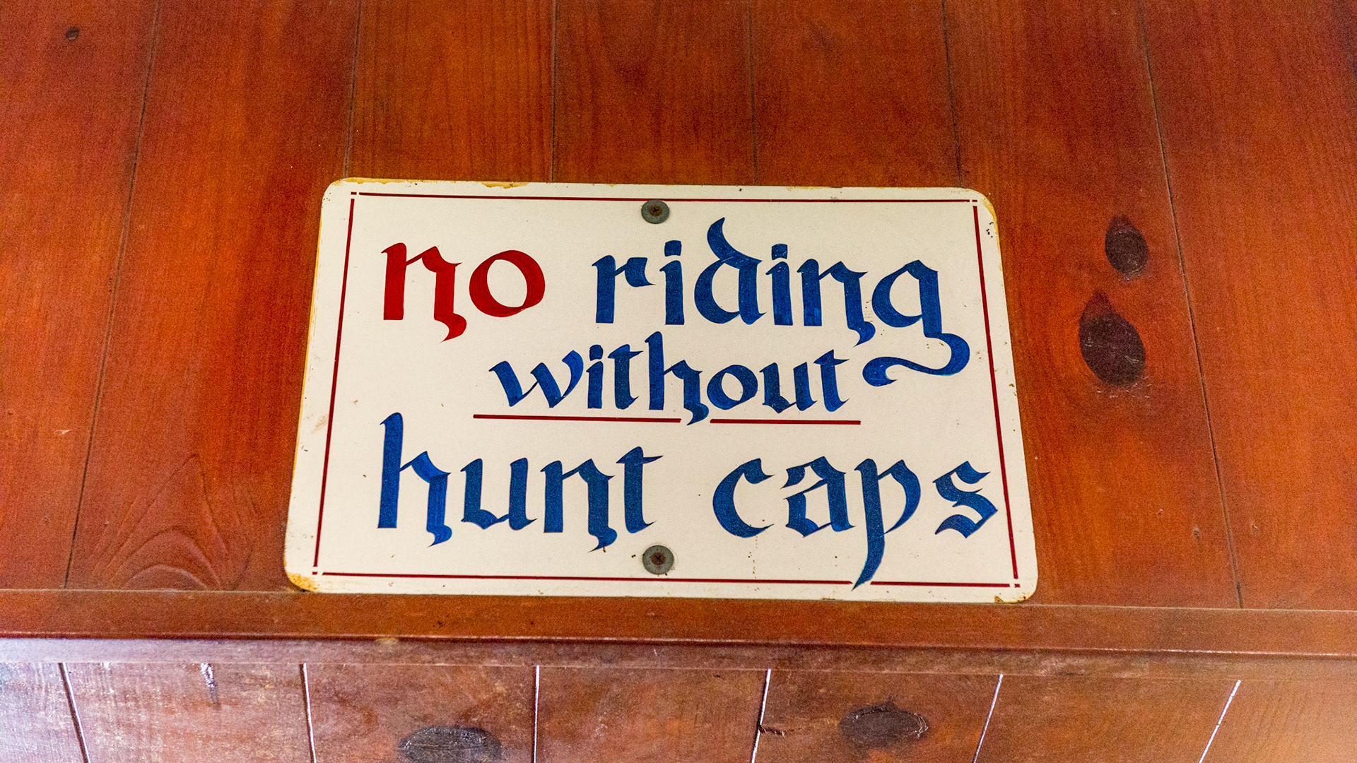 This is a very old sign in a barn, before designer helmets. Yet the message is still clear today. Wear a helmet when riding.