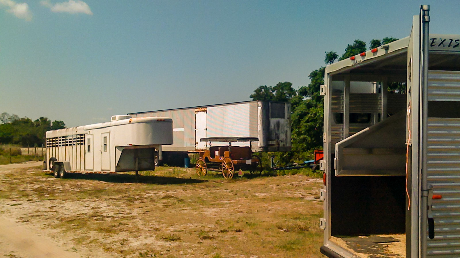 These are two types of common horse trailers without loading ramps.  They are called step[ ups.  You can see the divider through the back of the open trailer where the horses are partitioned in a slant way across the width of the trailer.