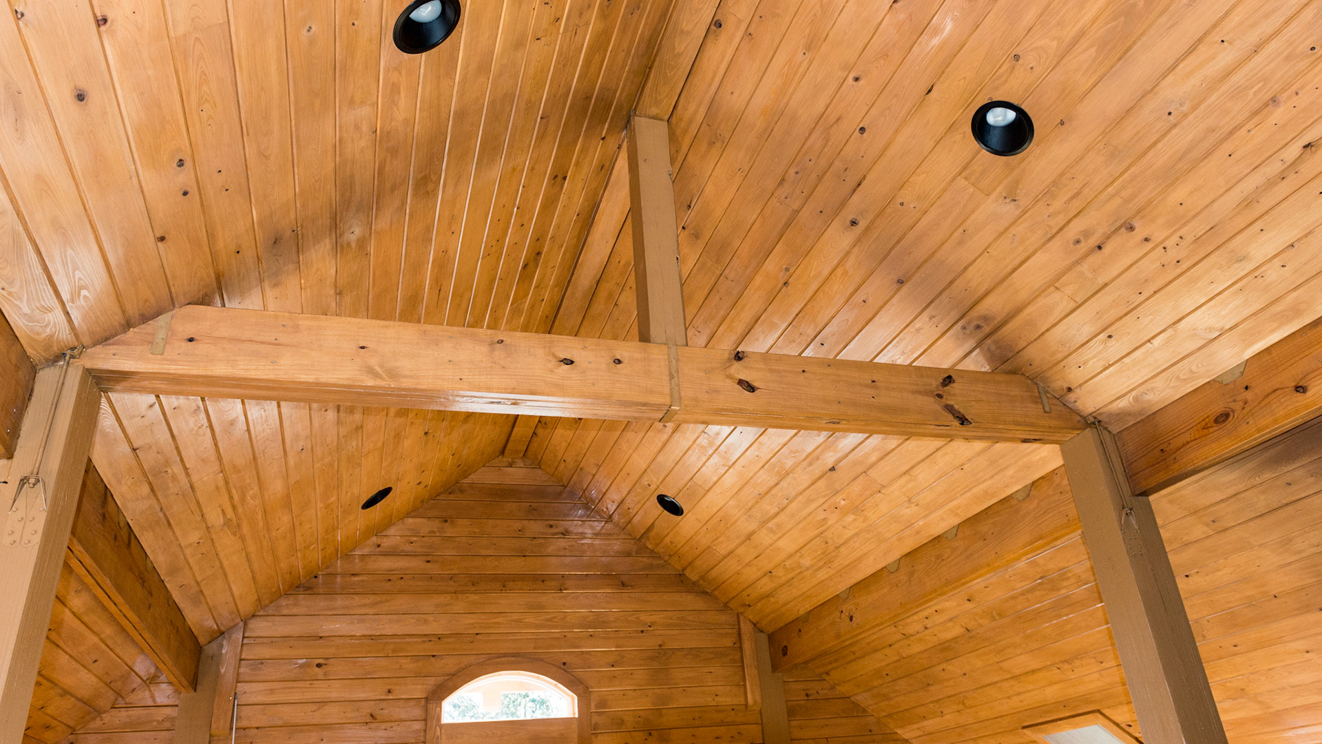 Roof structure seen in the loft which is wide open for a barn loft party with a door to a balcony.