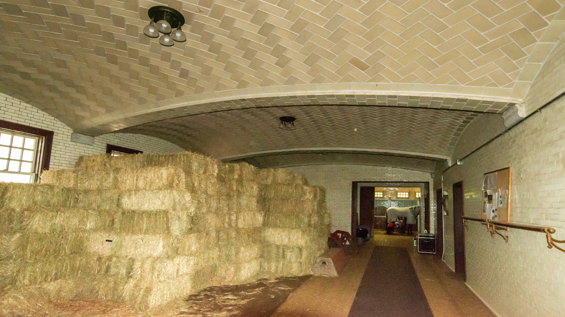 Vaulted ceilings like Grand Central Station in NYC. This was where the carriages were parked. A famous barn in CT that was built in the 1940's by the same archetect used in the building of Grand Central Station in NYC.  Hay is stacked neatly near the stalls.