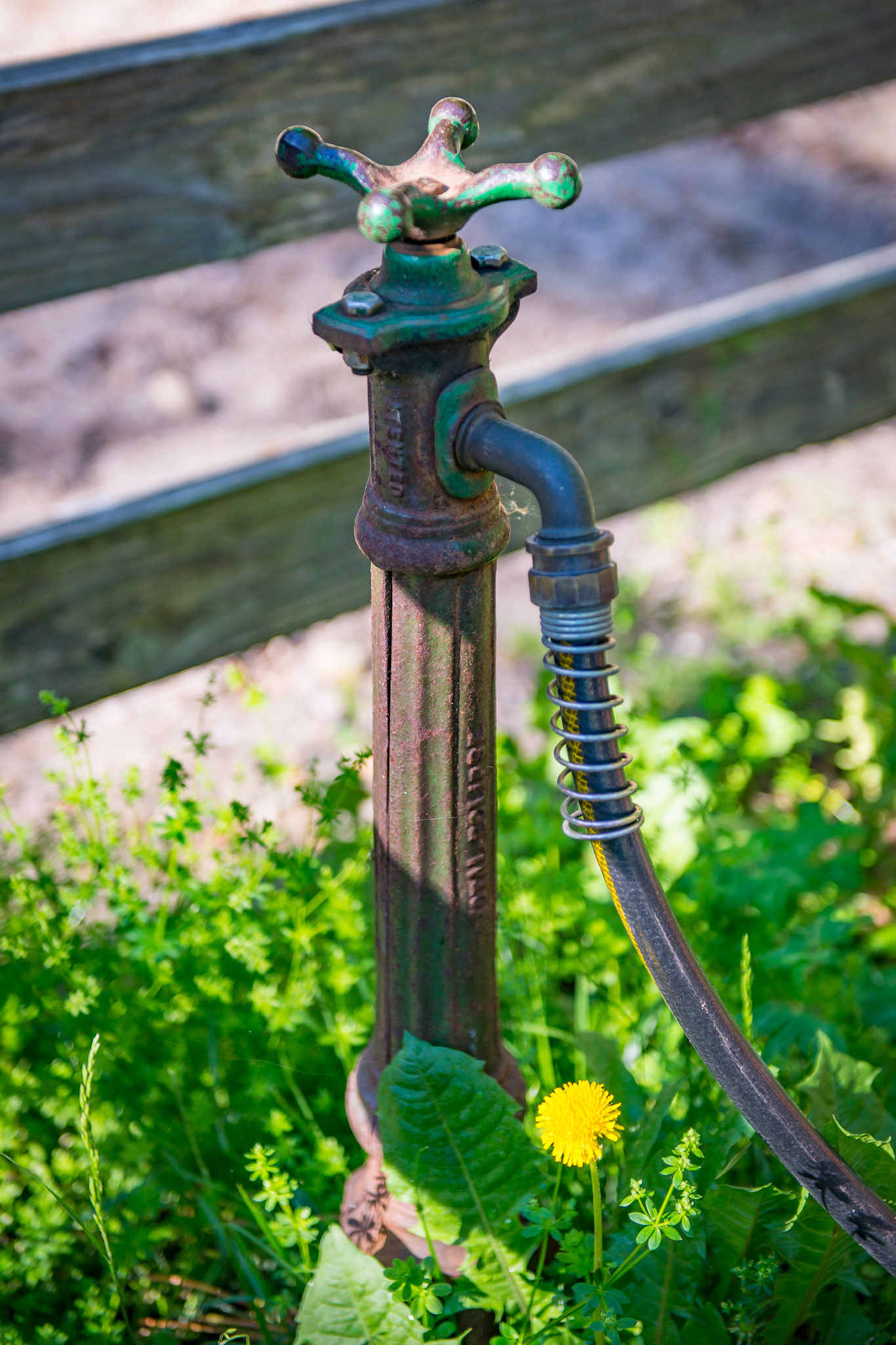 An antique hydrant being used on a farm in New York. The gasget is made of leather.  The valve is 3 feet below the surface and turning the handle opens it.