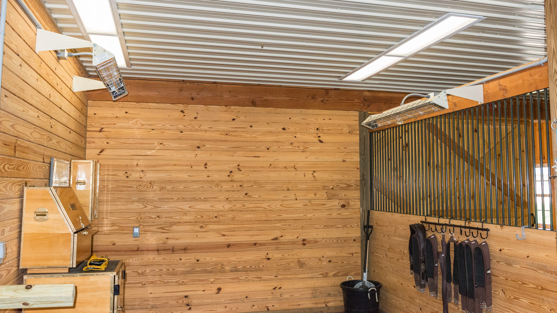 Grooming stall with 2 electric radiant heaters and 2 ceiling lights located offset from center. This provides for great lighting of the sides of the horse as well as avoids light damage if a horse rears.