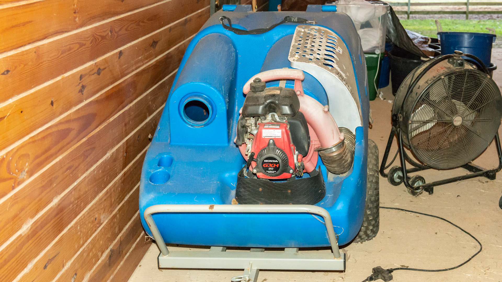 The Greyston manure vaccuum is pulled with a small riding tractor. A large diameter hose is attached to the hole next to the engine. While driving through the paddock, the end of the hose is directed over a manure pile and sucked into the blue container.  Manure can then be composted and used on the garden.