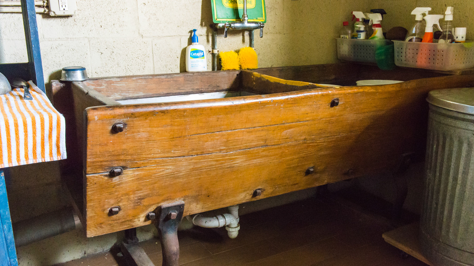 A wooden antique feed trough turned into a sink with stainless steel inserts.