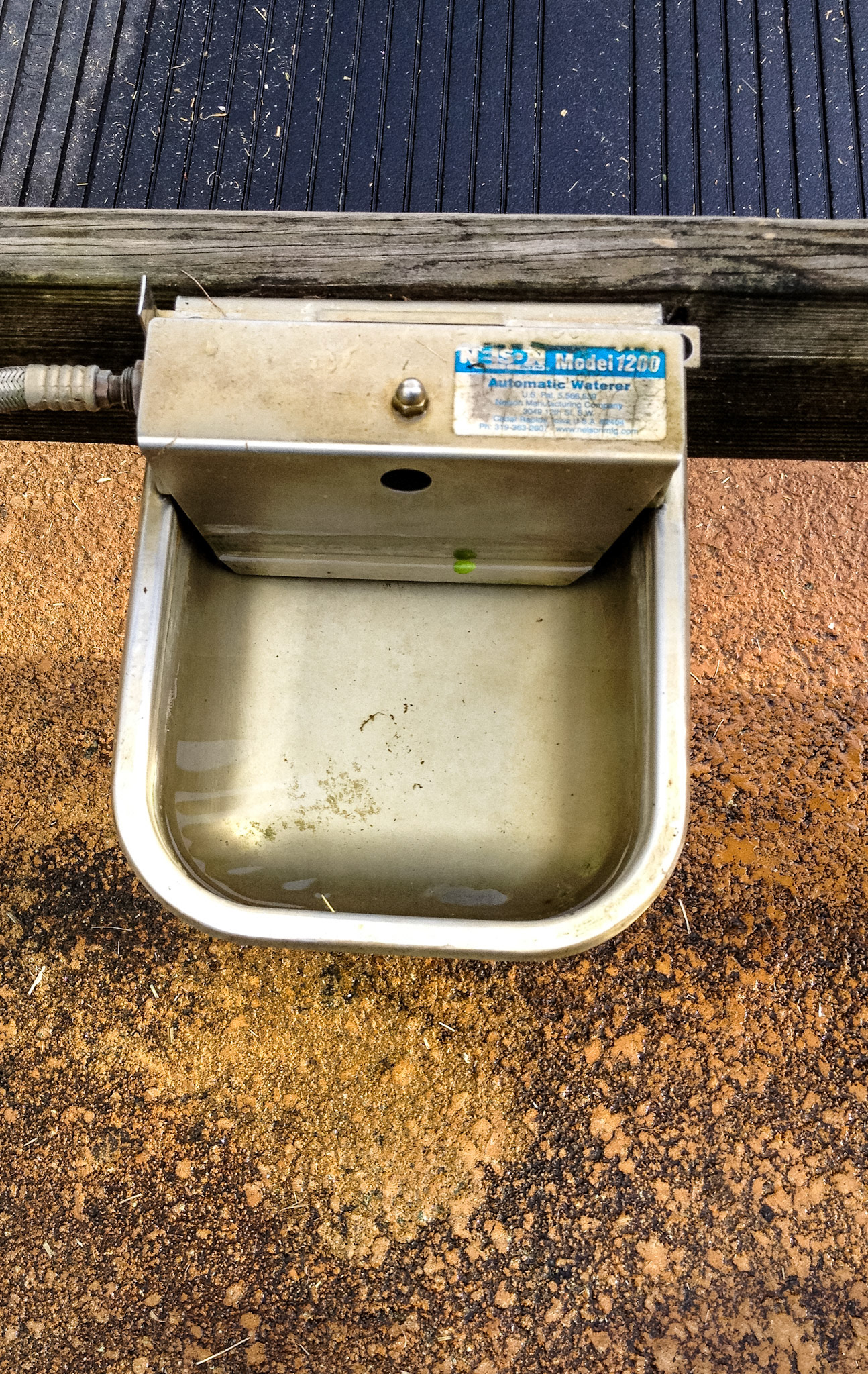 A dog automatic water bowl on a wash rack outside the barn.