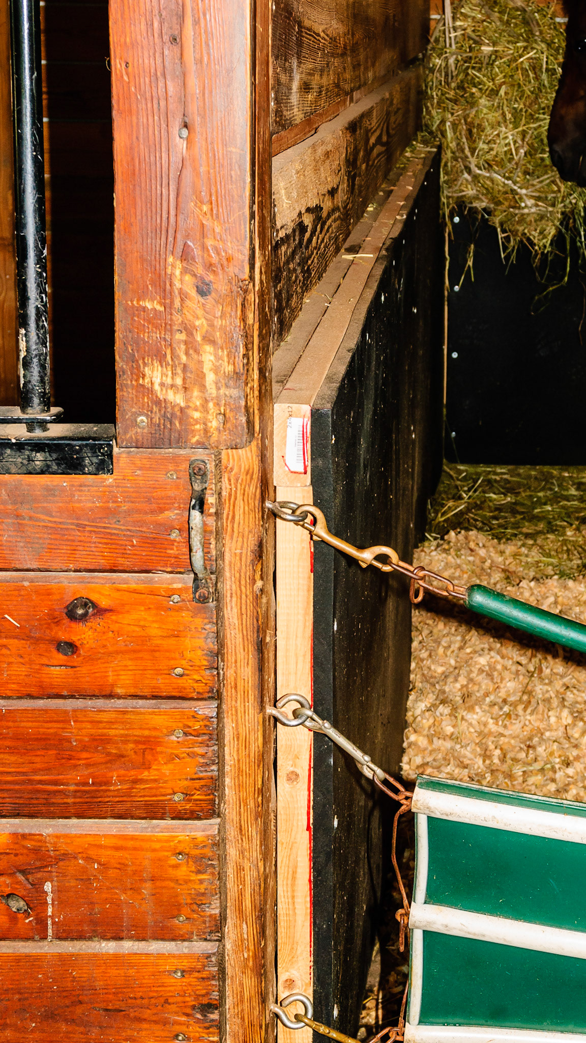 Usually kick mats are screwed or glued directly to the wall. This man’s idea was to buffer the kick by placing the mat away from the wall. He eventually removed it because the shavings worked their way up behind the mat.  Maybe if the bottom edge was about a foot off the ground it would not have been a problem. I thought the idea was good to prevent injury to the horse.