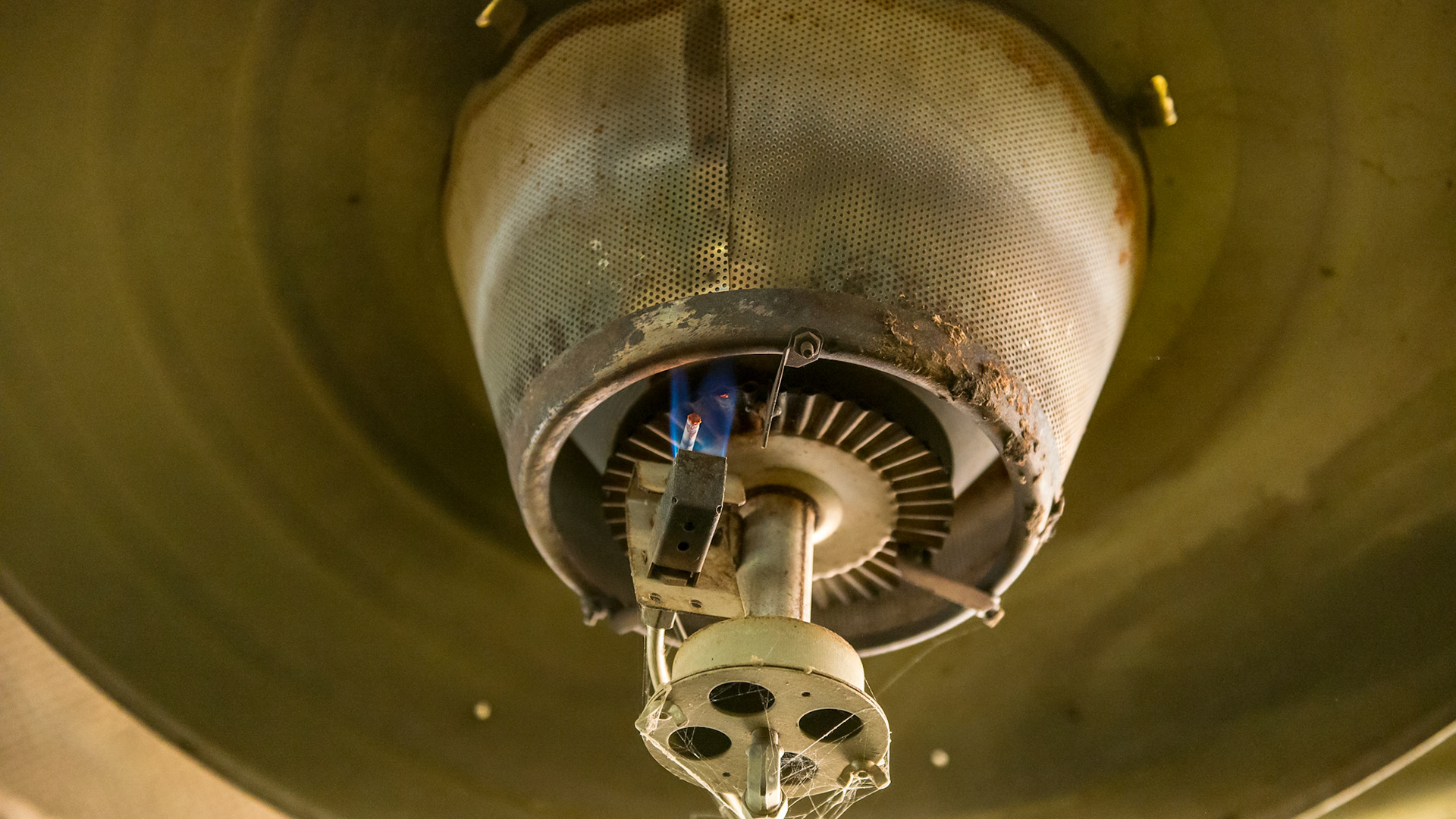 A live flame is seen in this image of a heater hanging over the wash stall of a barn.