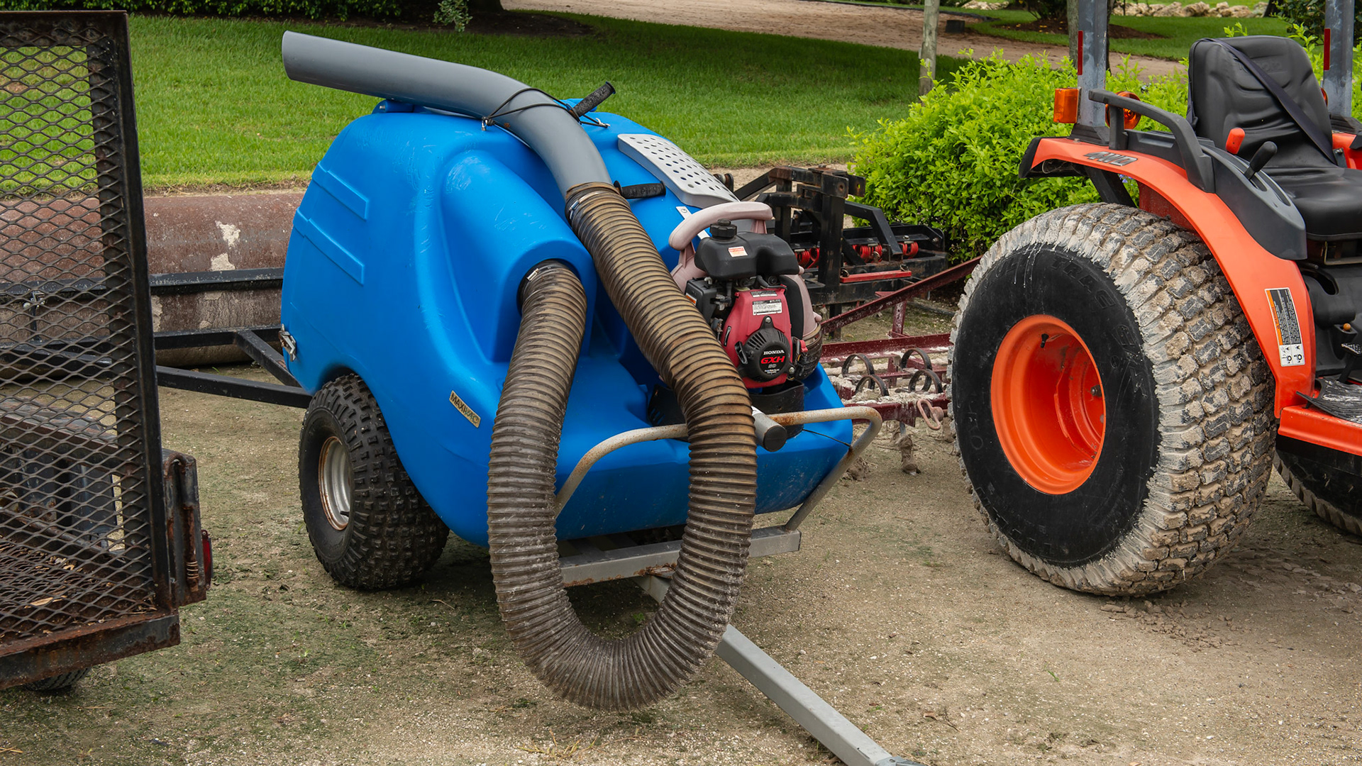 A Greystone manure vacuum with hose attached.  The black handle attached to the hard plastic helps the operator sitting on the pulling tractor to aim the tip to the pile.
