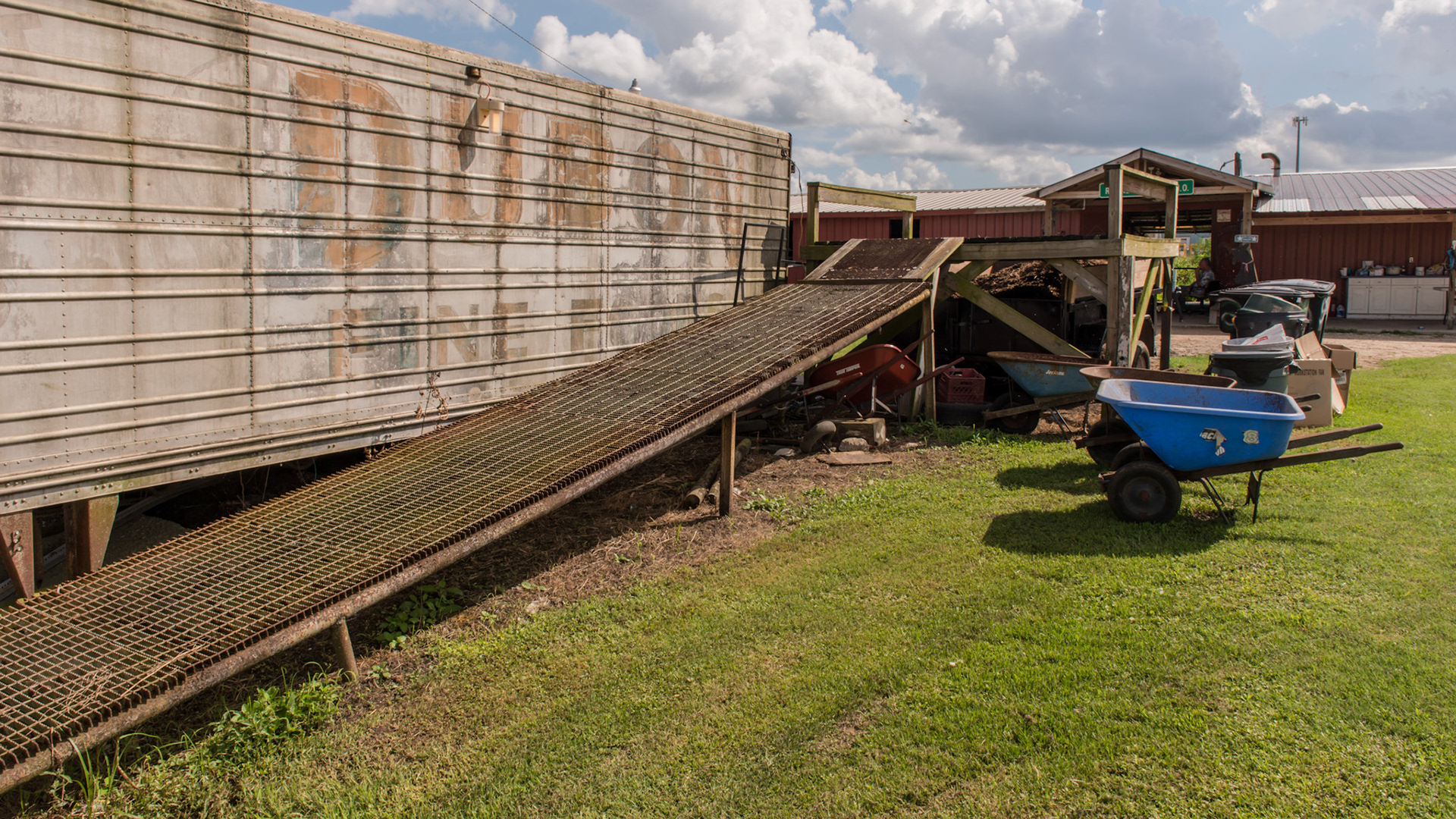 Ramp to manure platform made of steel decking. One person said it is very slippery when wet.  There are no sides and the end makes a steep up angle.  Pusing the large blue wheel barrow could be difficult for some people.  This is a dangerous set up.