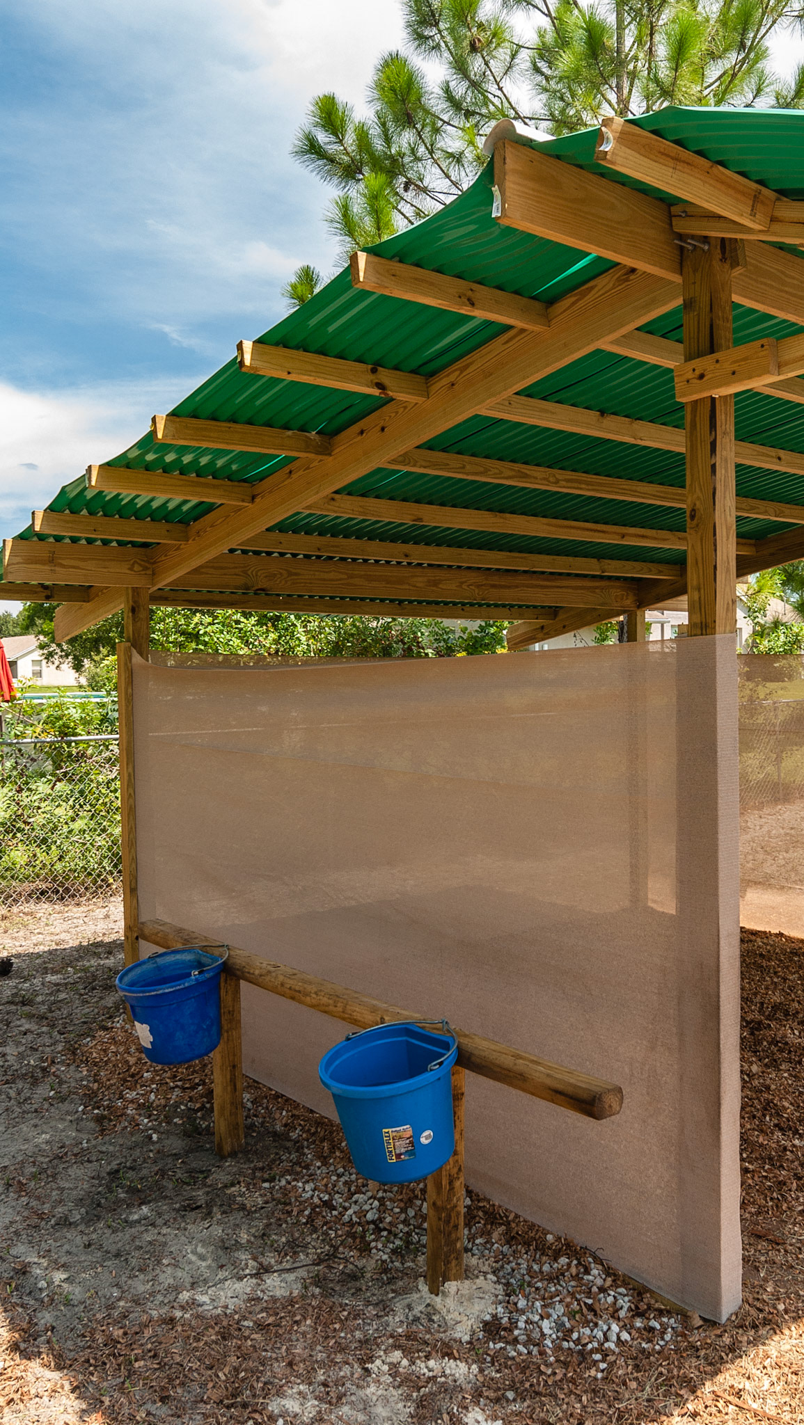 Hanging feed buckets. Mesh winf and sun narrier. Interesting roofing material.
