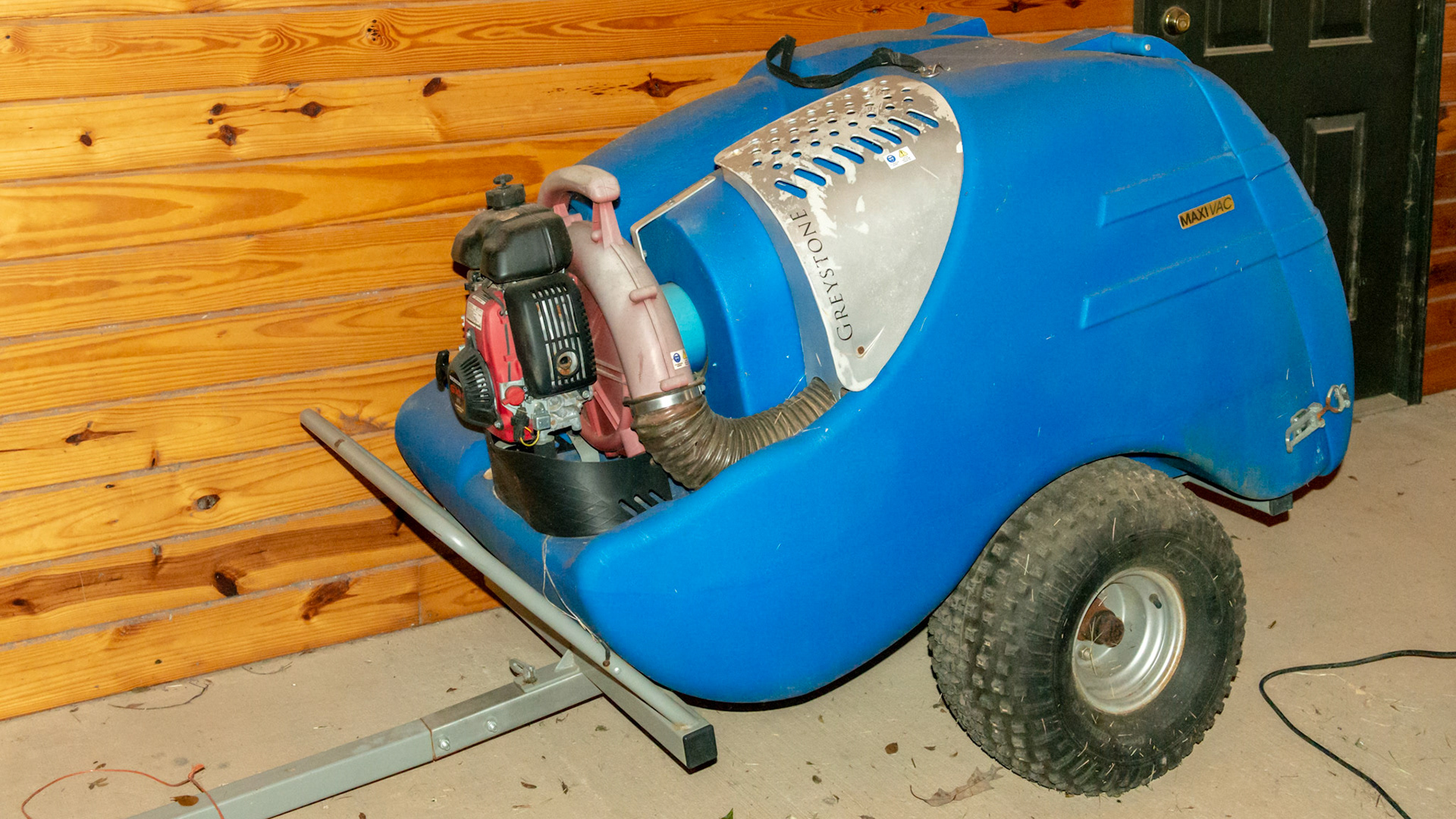 The Greyston manure vaccuum is pulled with a small riding tractor. A large diameter hose is attached to the hole next to the engine. While driving through the paddock, the end of the hose is directed over a manure pile and sucked into the blue container.  Manure can then be composted and used on the garden.