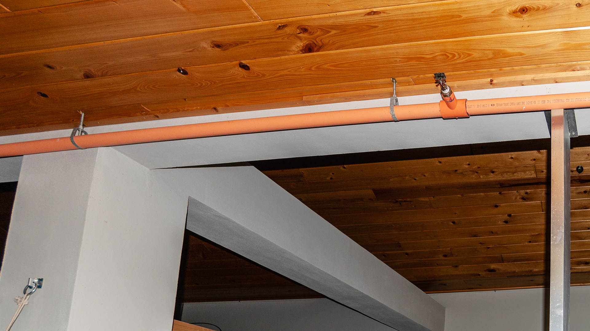Sprinkler systems inside a barn. An orange plastic pipe dedicated to the fire sprinkler system