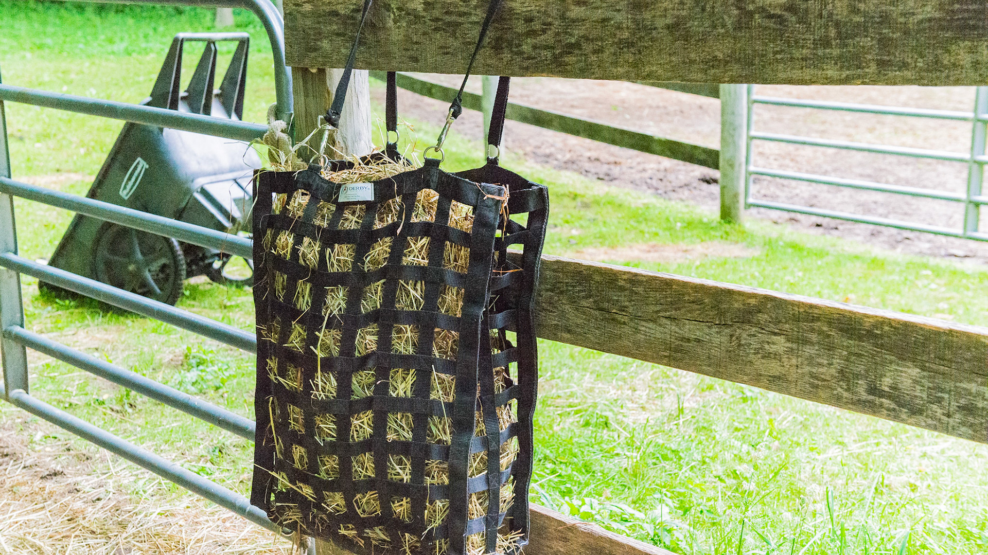 A hay bag hung on the fence for outdoor use.