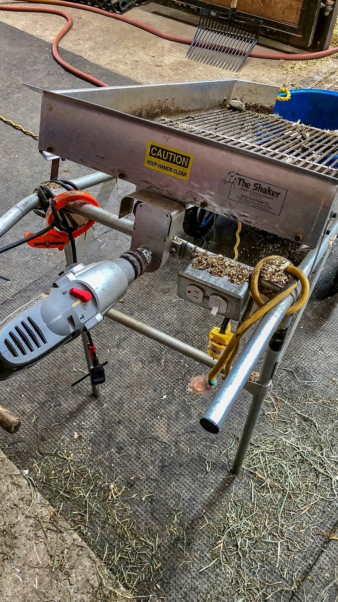The Shaker is a noisy device run by a high speed drill that sifts the dirty shavings allowing the small dry flakes to fall back into the stall while the larger manure balls roll into the wheel barrow.  With a bit of time, the wet flakes become dry.