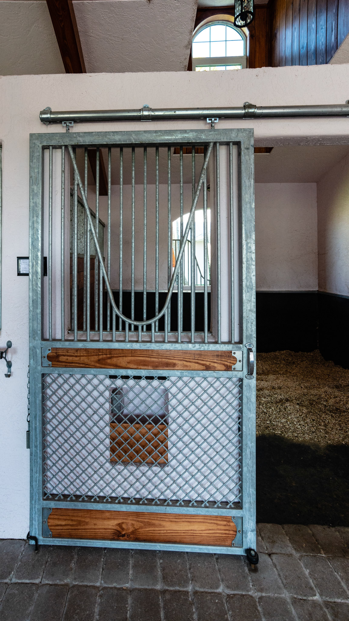 One piece steel rolling stall door with a cut away for the horse to hang his head out of the stall. This design is sturdy and provides for ventilation from the top to the bottom. There is no space at the bottom for a hoof to get caught.