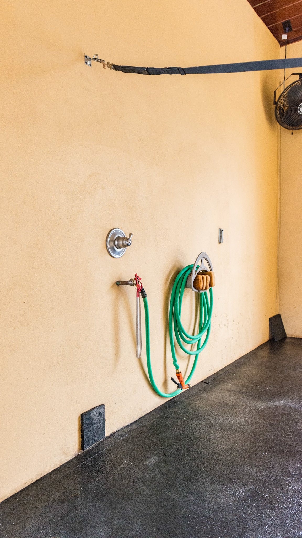 A rubber block attached to the wash stall near the floor acts as a bumper when the cross ties drop away from the horse.