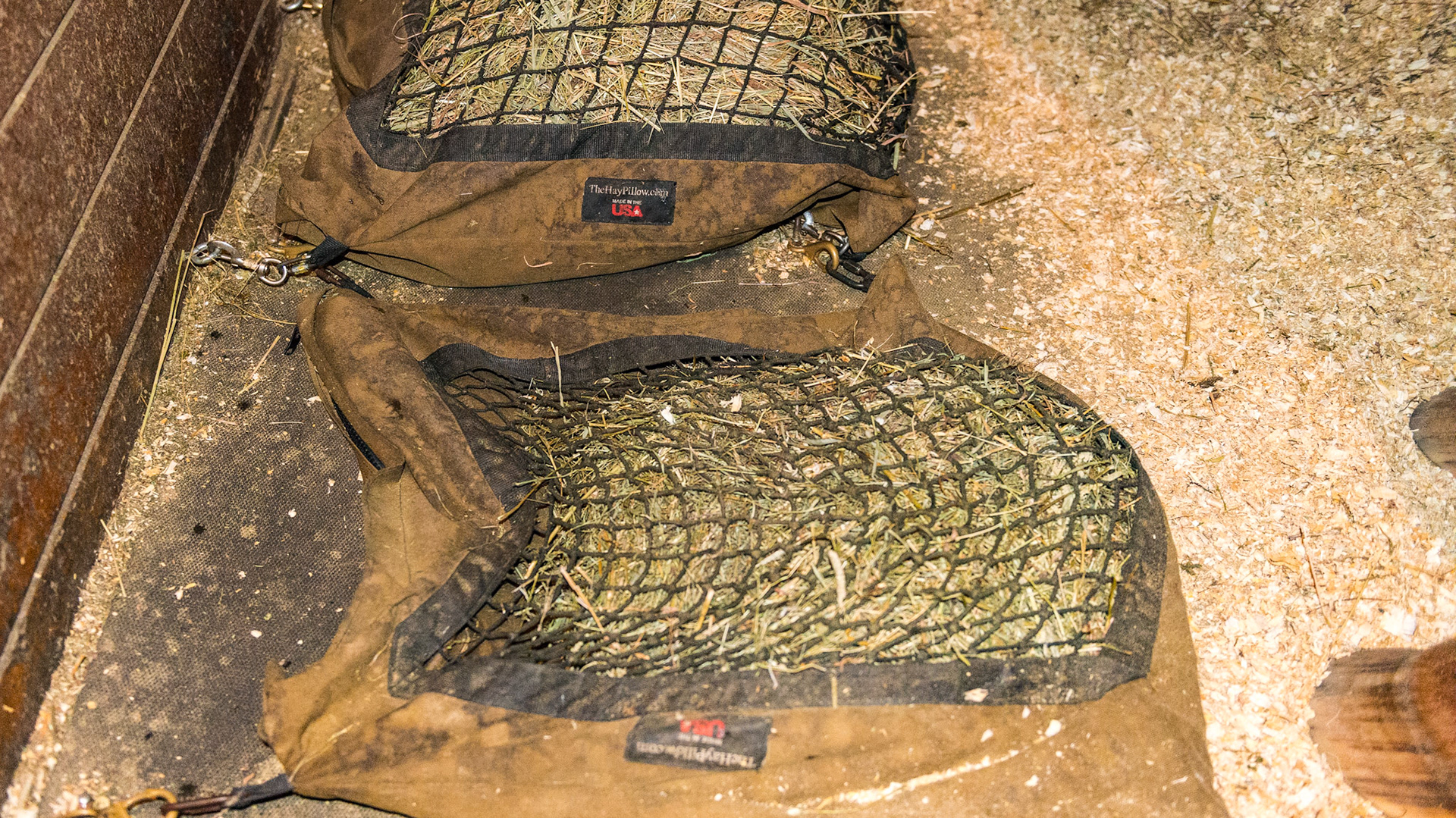 These Hay Pillows are secured to the floor with no reported problems other than the horse occasionally stepping on the front latches that would break them. Also, the Pillow nearset me has smaller holes for the leafier hay while the farther Pillow has larger holes for regular hay.
