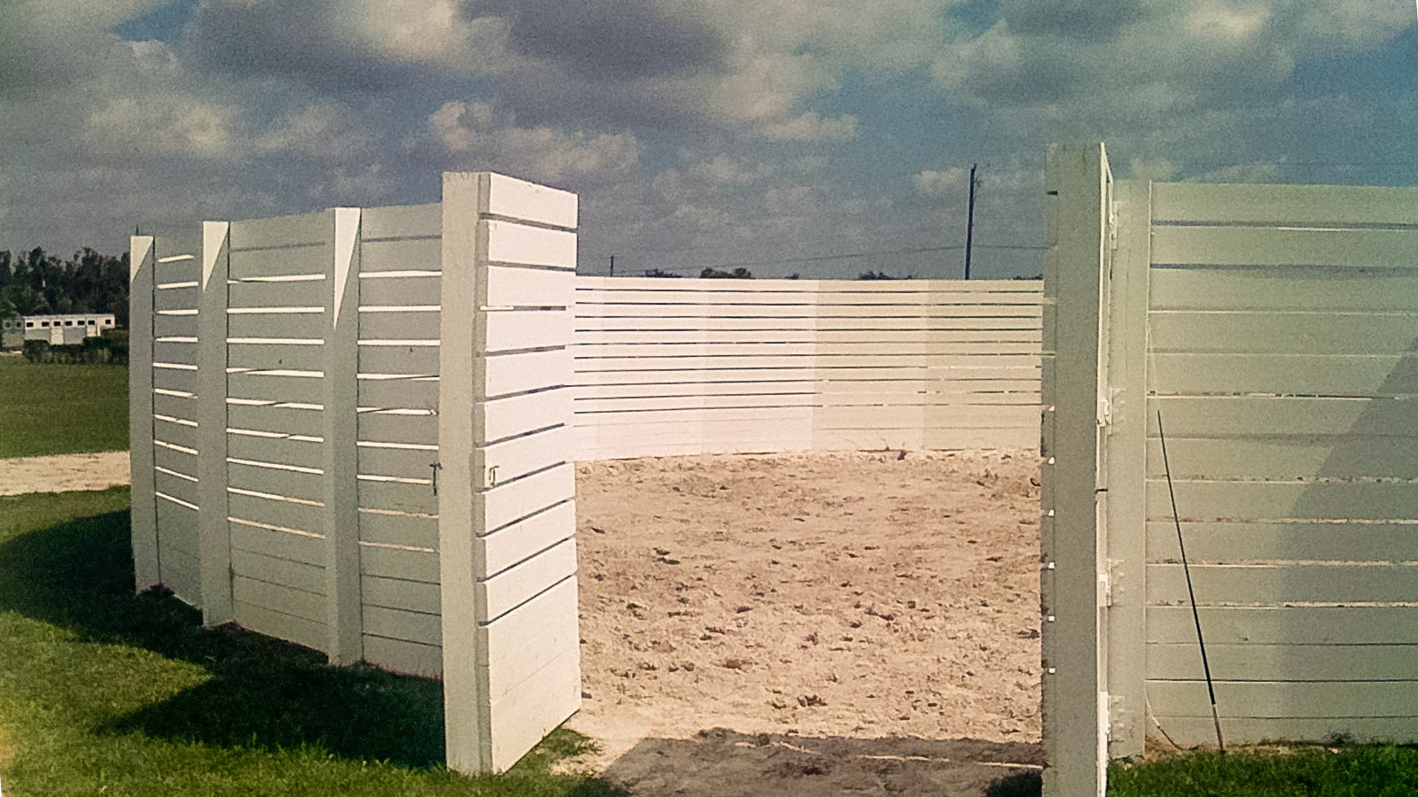 Outdoor round pen with very high walls to help focus the young horse to the task at hand.