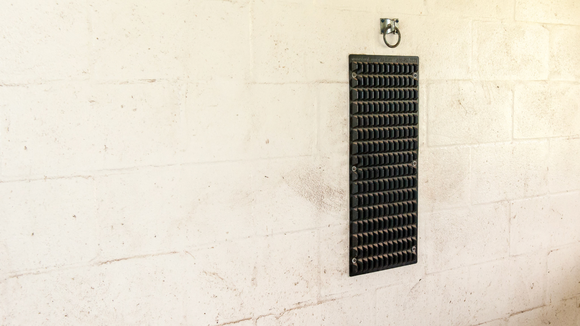 A rubbing pad mounted to the stall wall made of hard rubber.