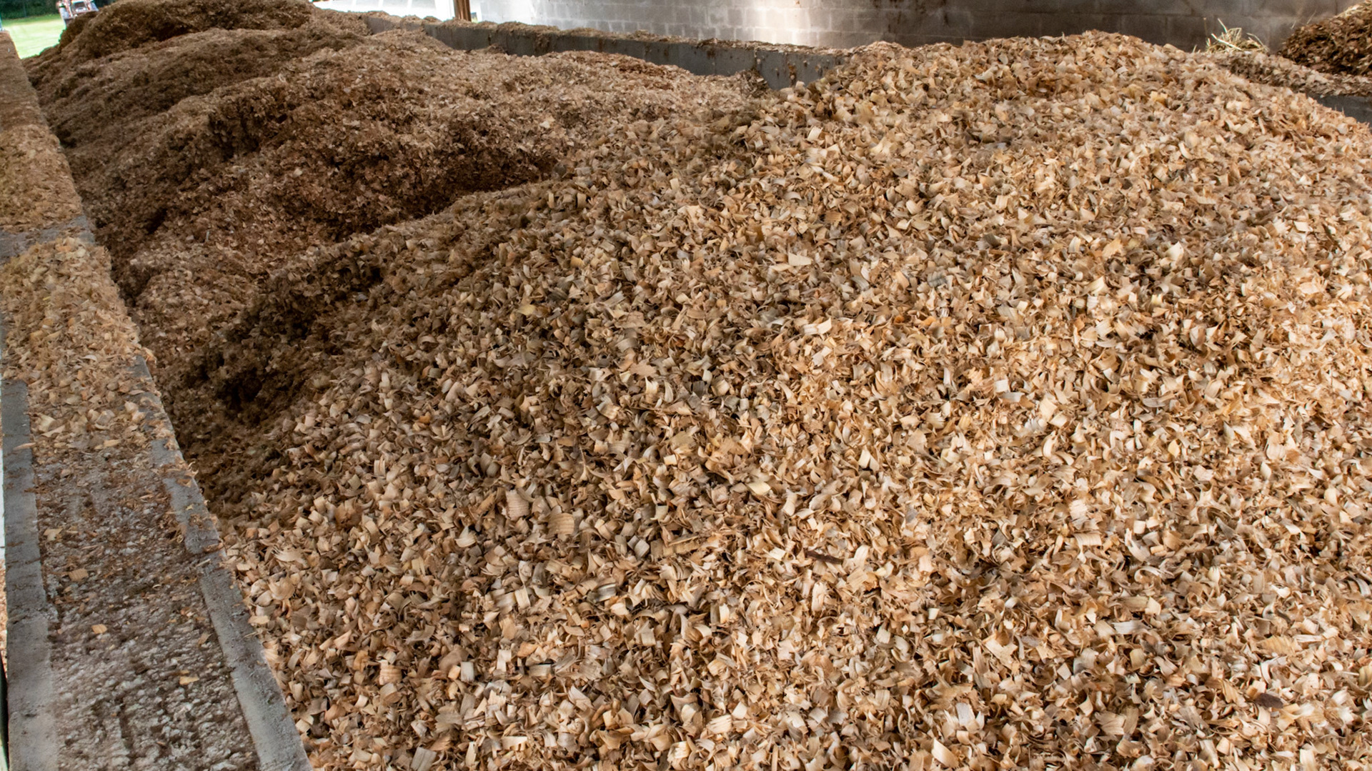 Close up of a large storage area for shavings and waste storage. A large front end loader is used to manouver the material.