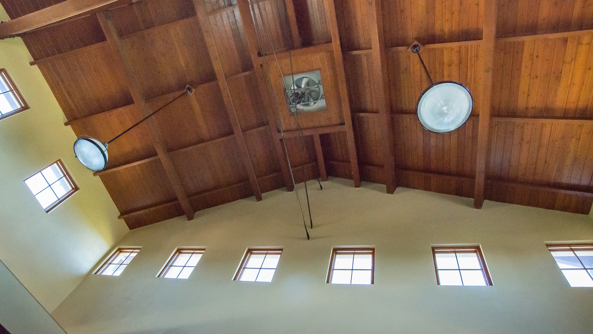 2 insect spray heads extending from the wall, hardwood ceiling with 1 of several exhaust fans.