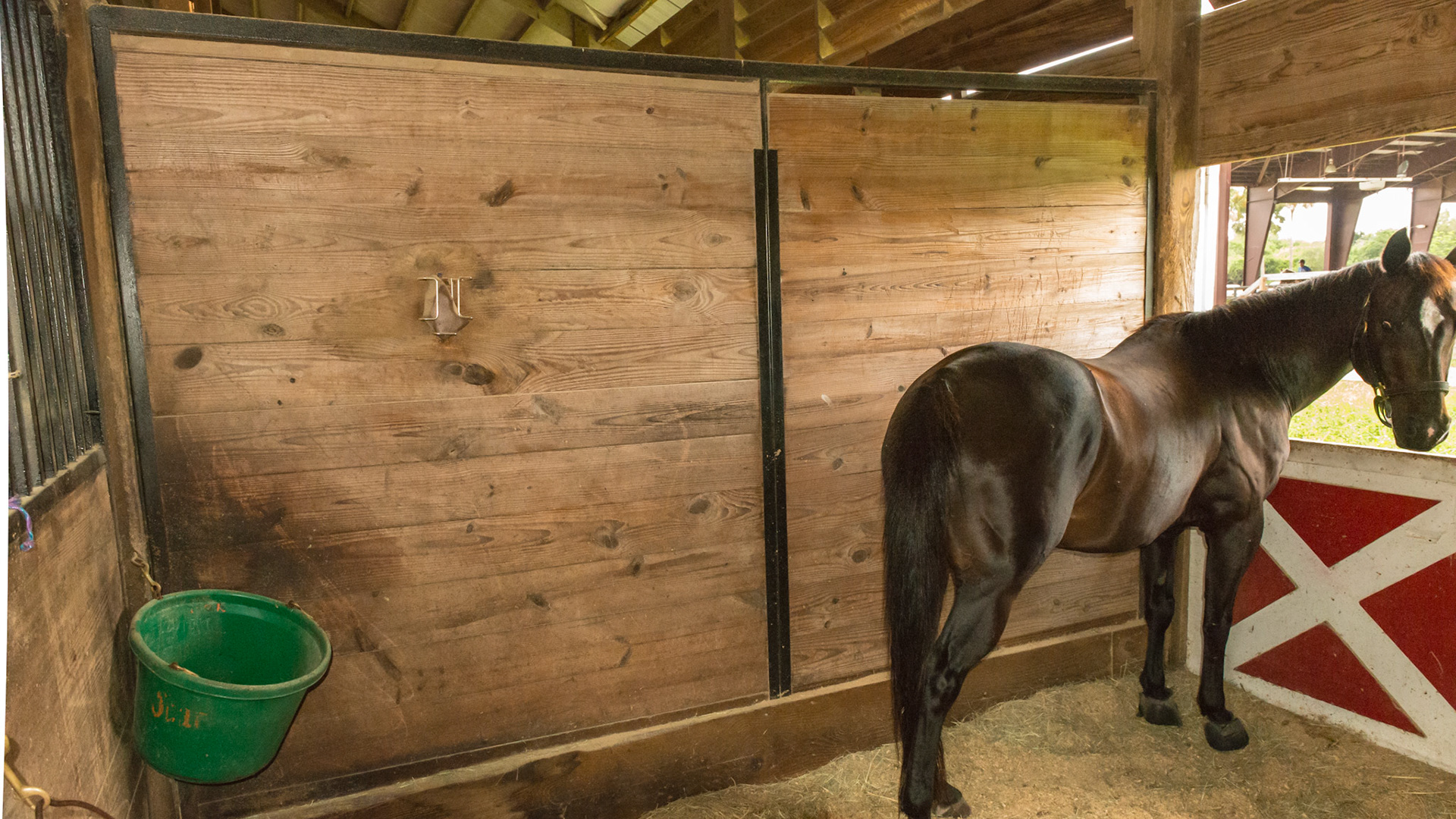 Stall wall has 2 sections providing stability in a steel frame. They are placed on a large beam laid across the stall floor.