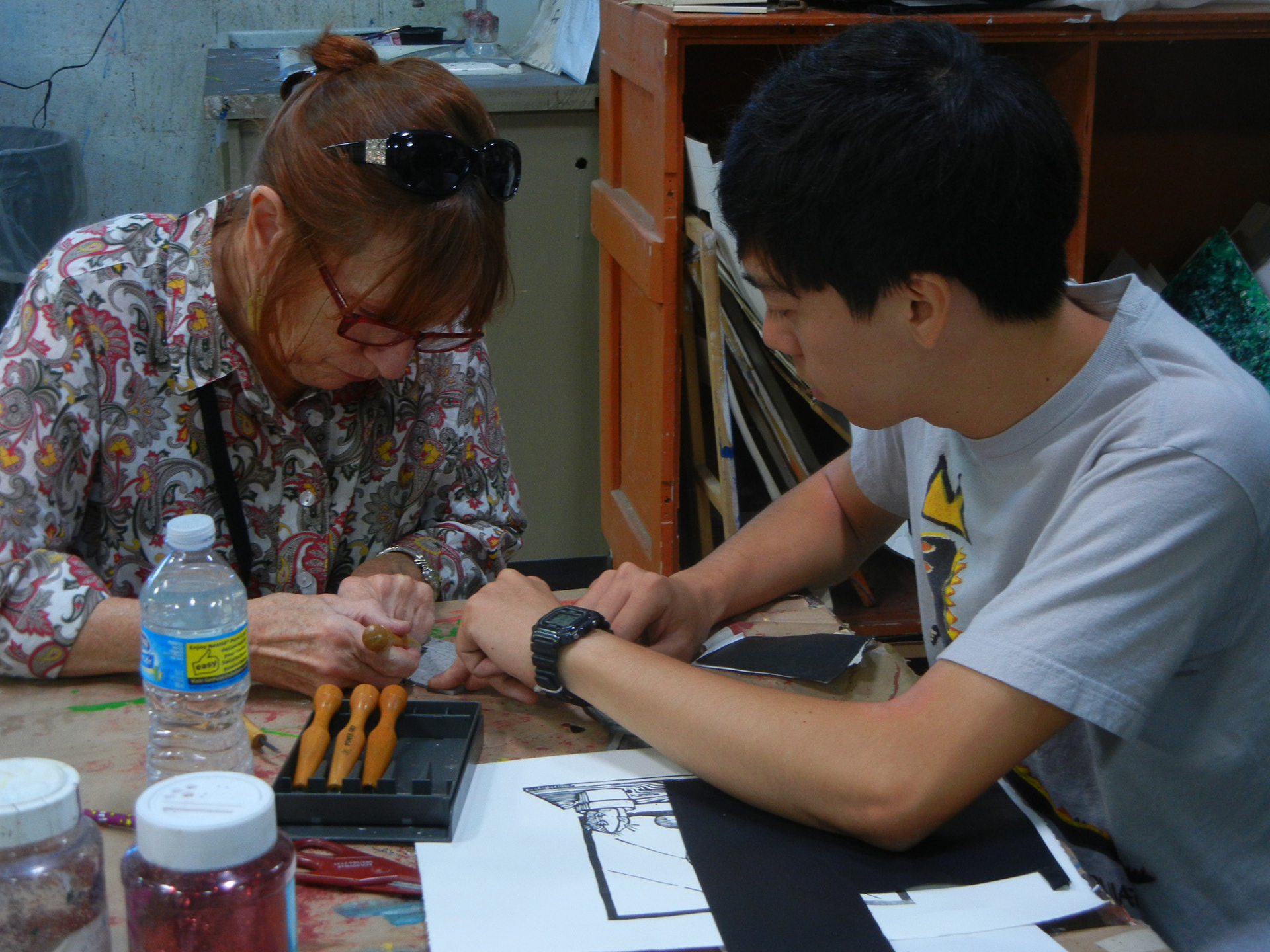 The UNM student helps the Art Street artist in making a linoleum cut plate at the Art Street.
