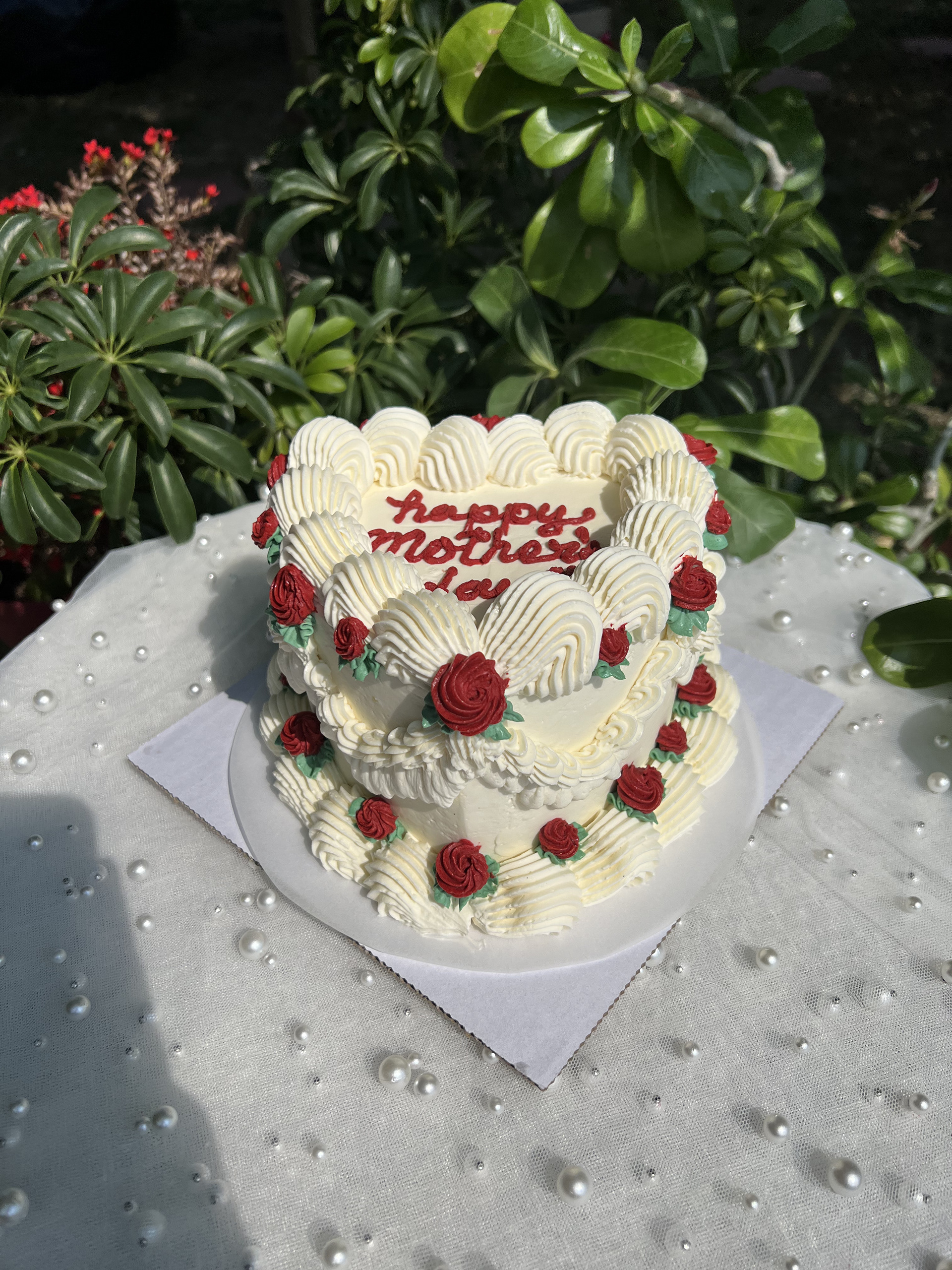 Heart shaped cake with piped cream and red flower details