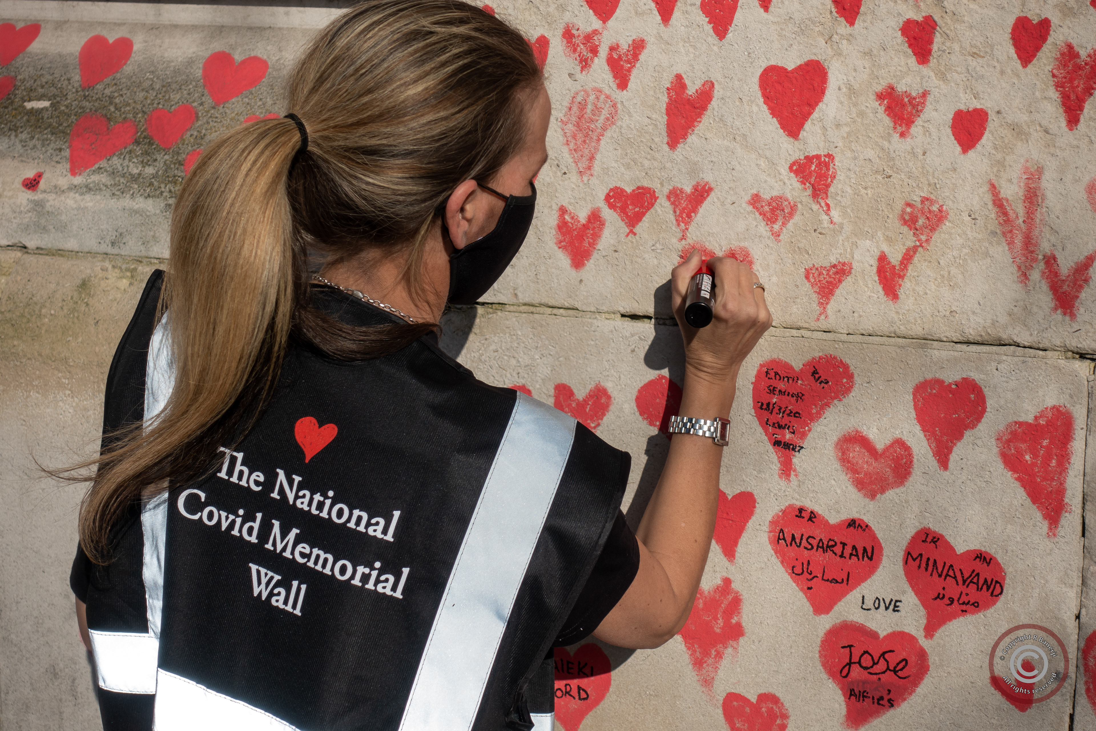 A woman draws her heart in tribute to the loss of loved ones to the Covid-19 pandemic, Westminster, London