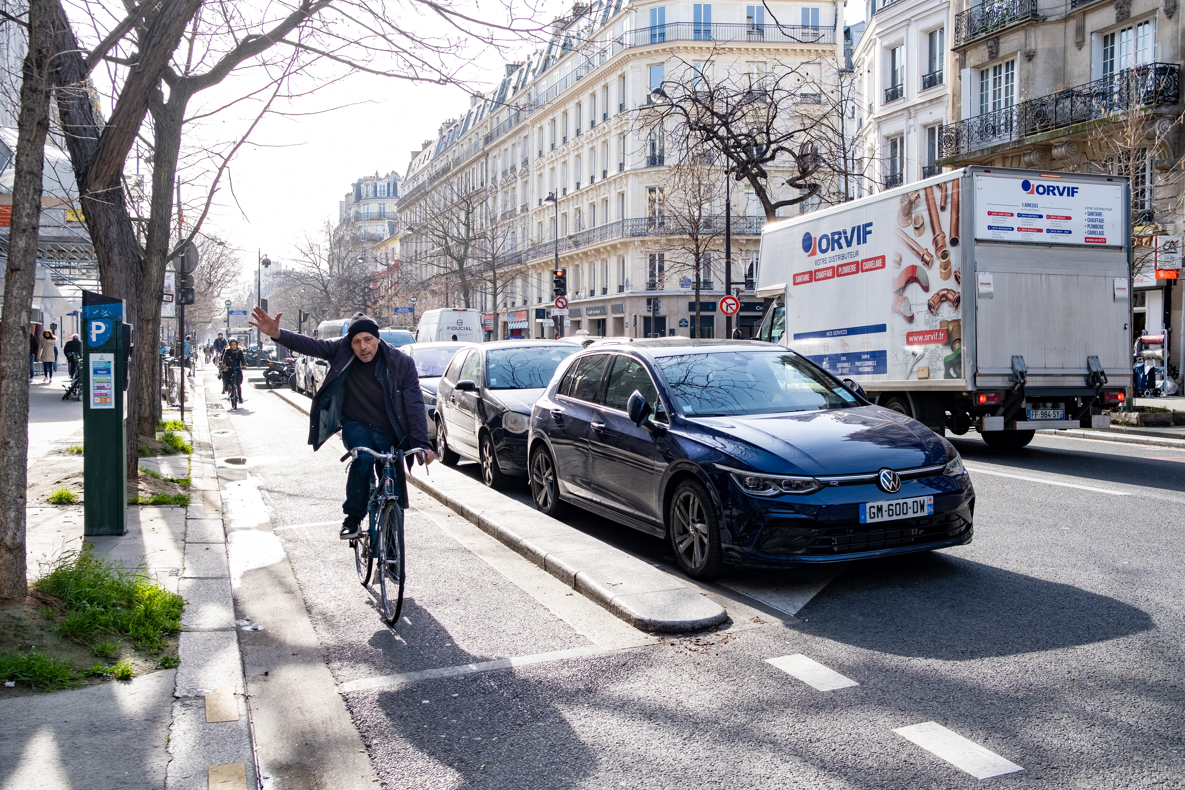 A man waves while cycling to work, Paris, France