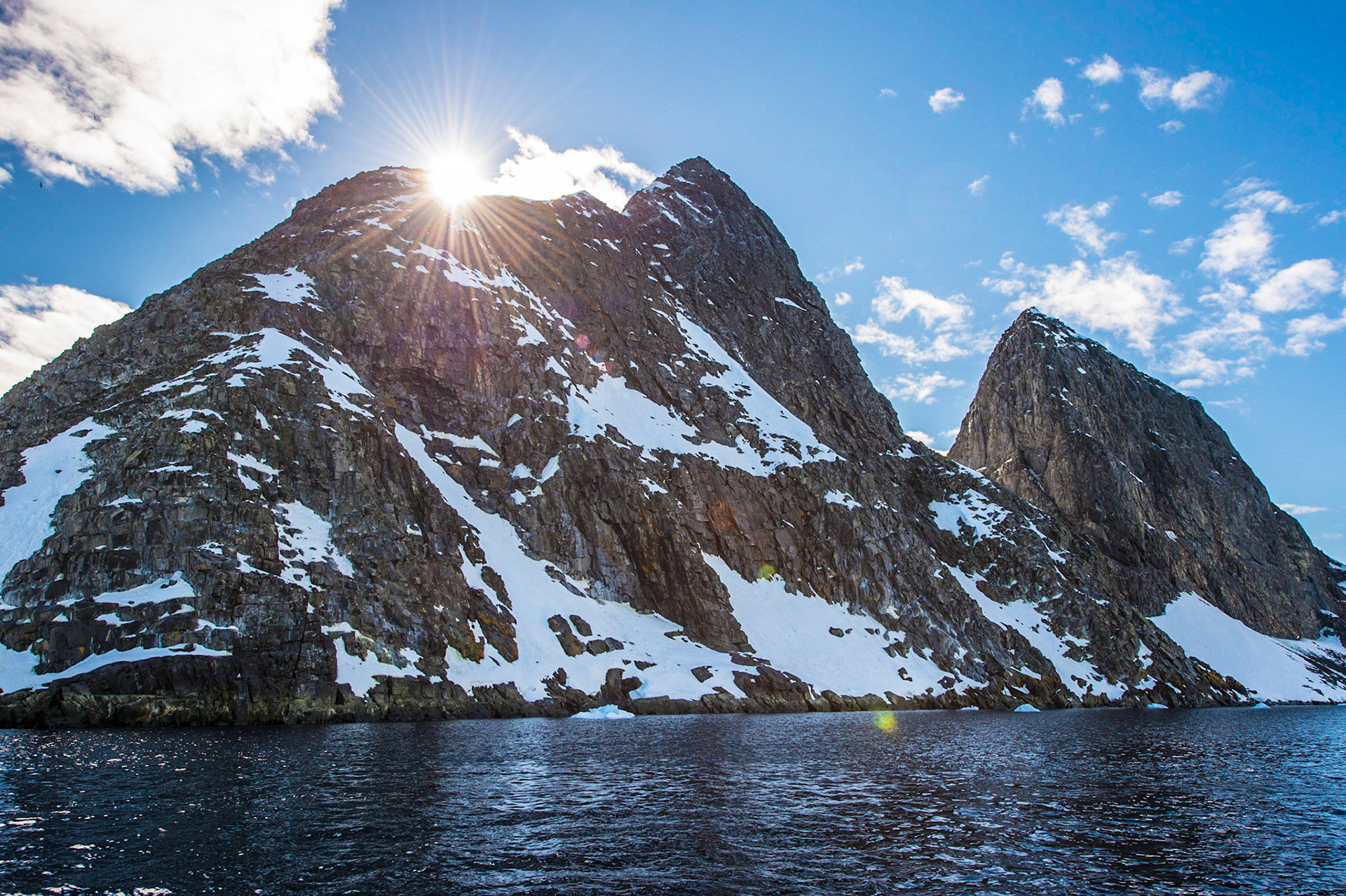 Sun flares over mountains near Astrolabe Island, Antarctica