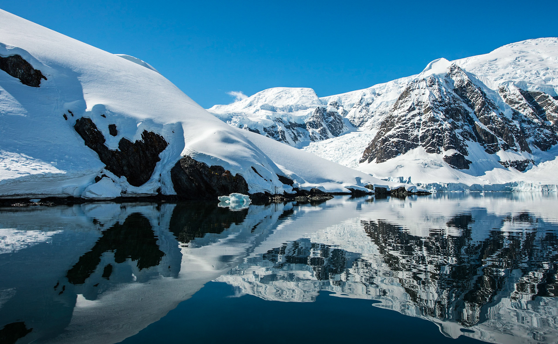 Snow covered mountains reflect in the water, Antarctica