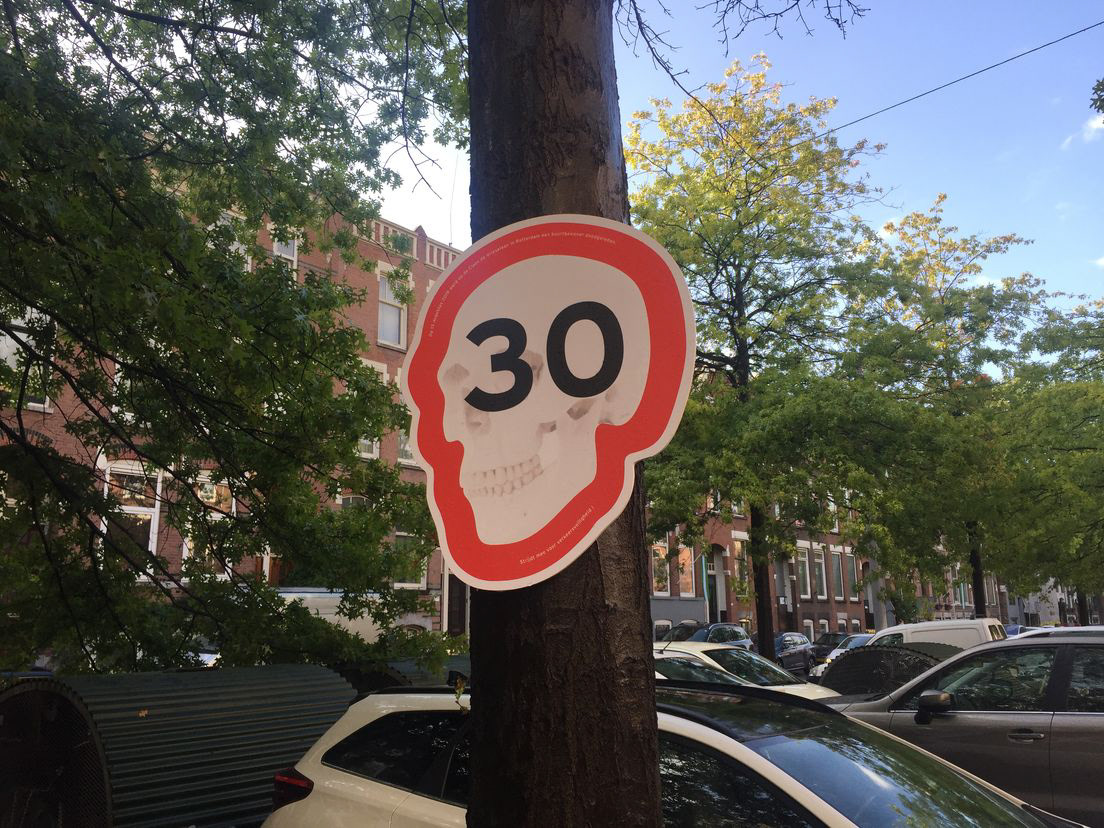 Protest sign at roadside mimicking a 30 KM sign while the white lower portion of the sign is actually a skull