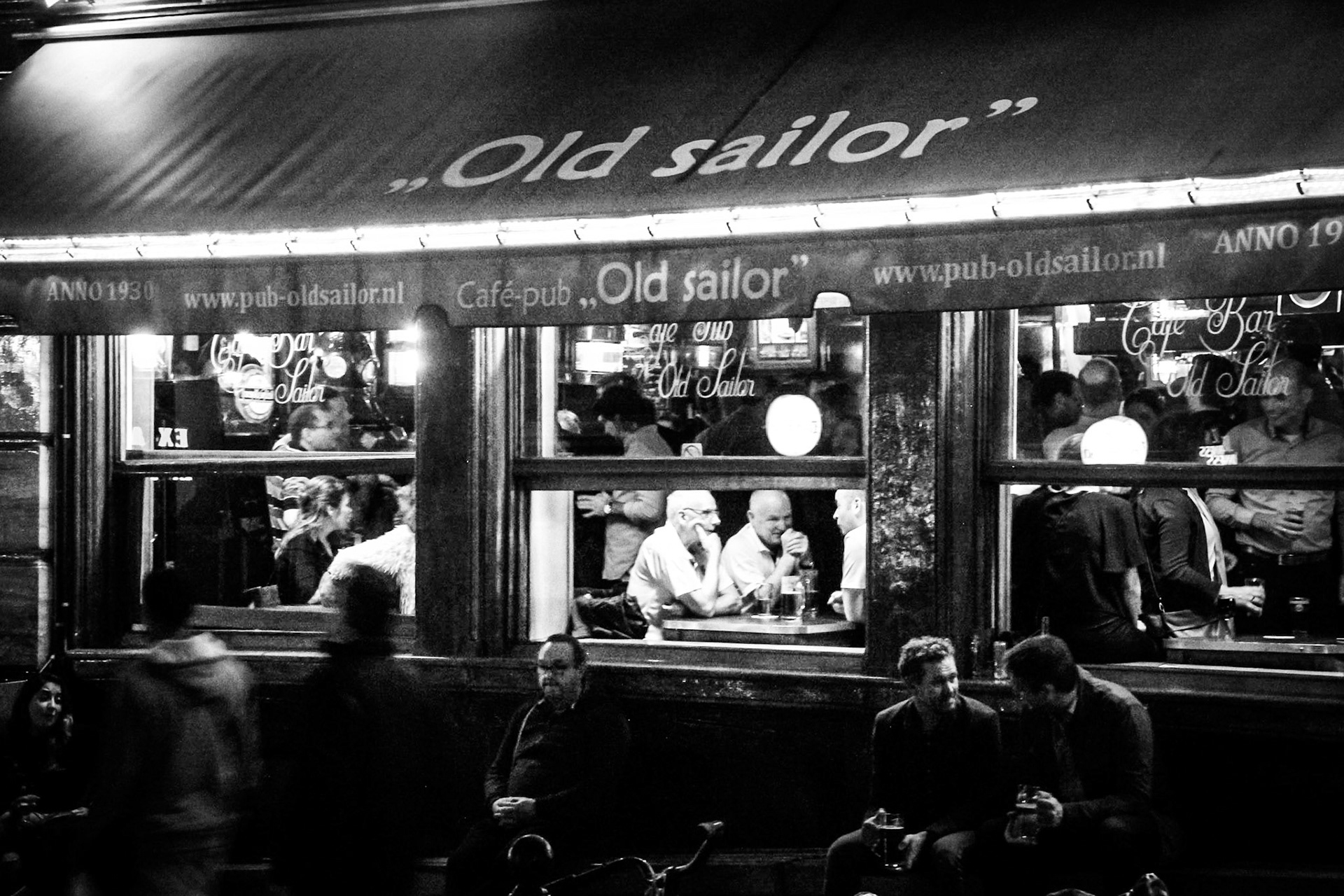 Old friends share a drink admidst the hustle and bustle of Amsterdam's Red Light District