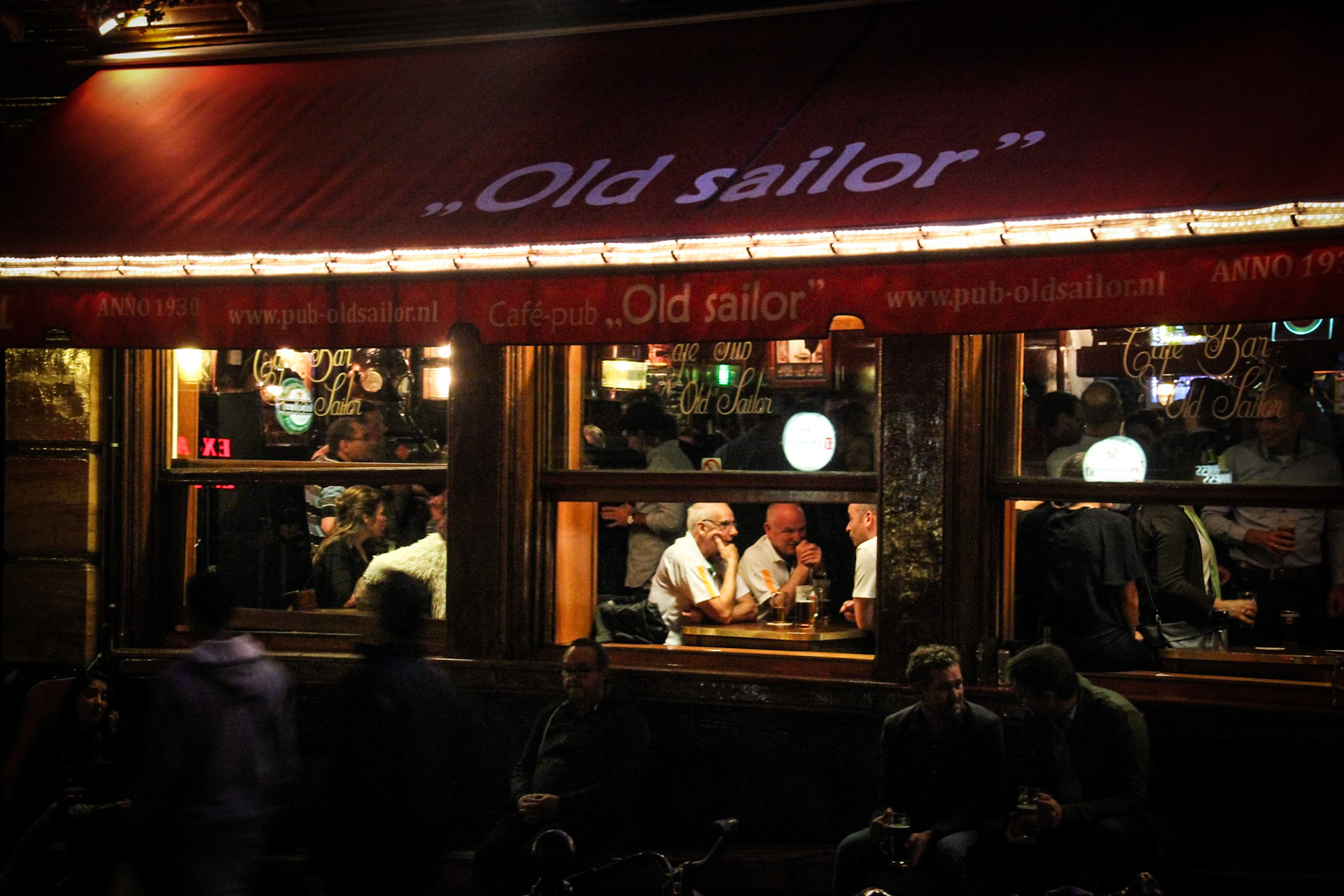 Old friends share a drink admidst the hustle and bustle of Amsterdam's Red Light District