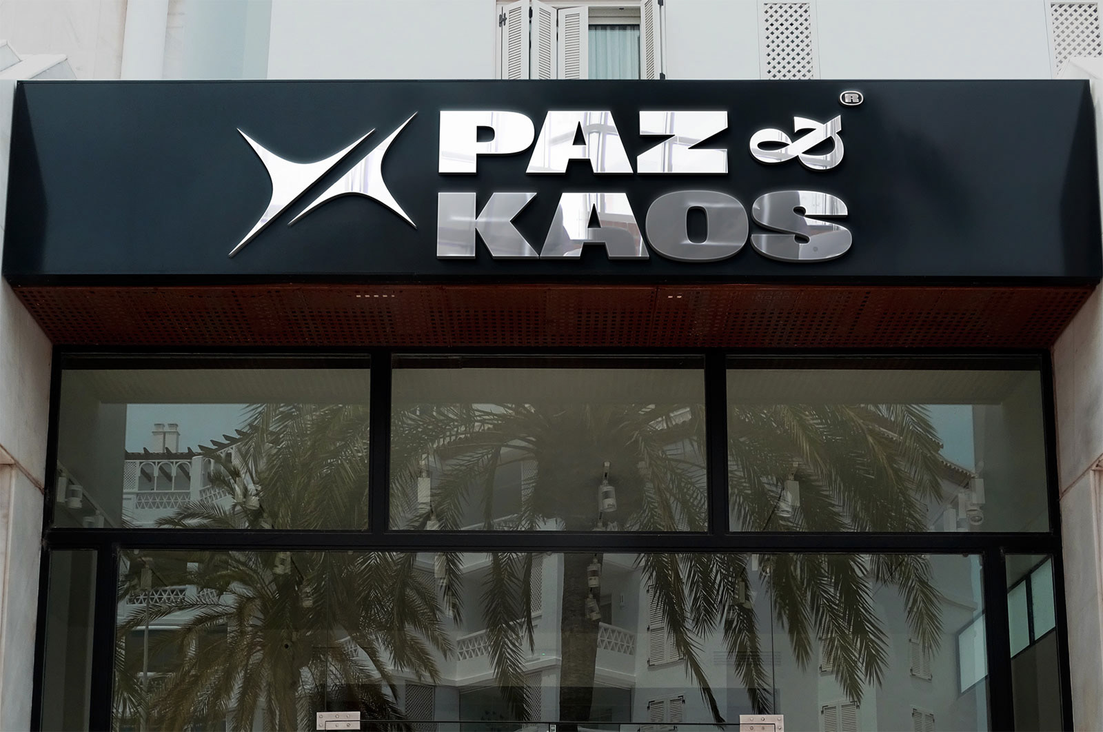 Fachada de loja com letreiro Paz&Kaos em metal cromado 3D sobre vitrine ampla - aplicação de identidade visual em arquitetura comercial
