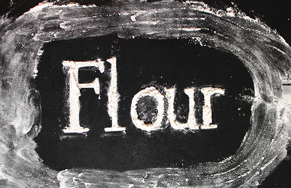 Title: Flour Description: Flour sprinkled through text cutout against black sketchbook Date: Fall 2024 Credits: Photography by Luisa F. Ligardo