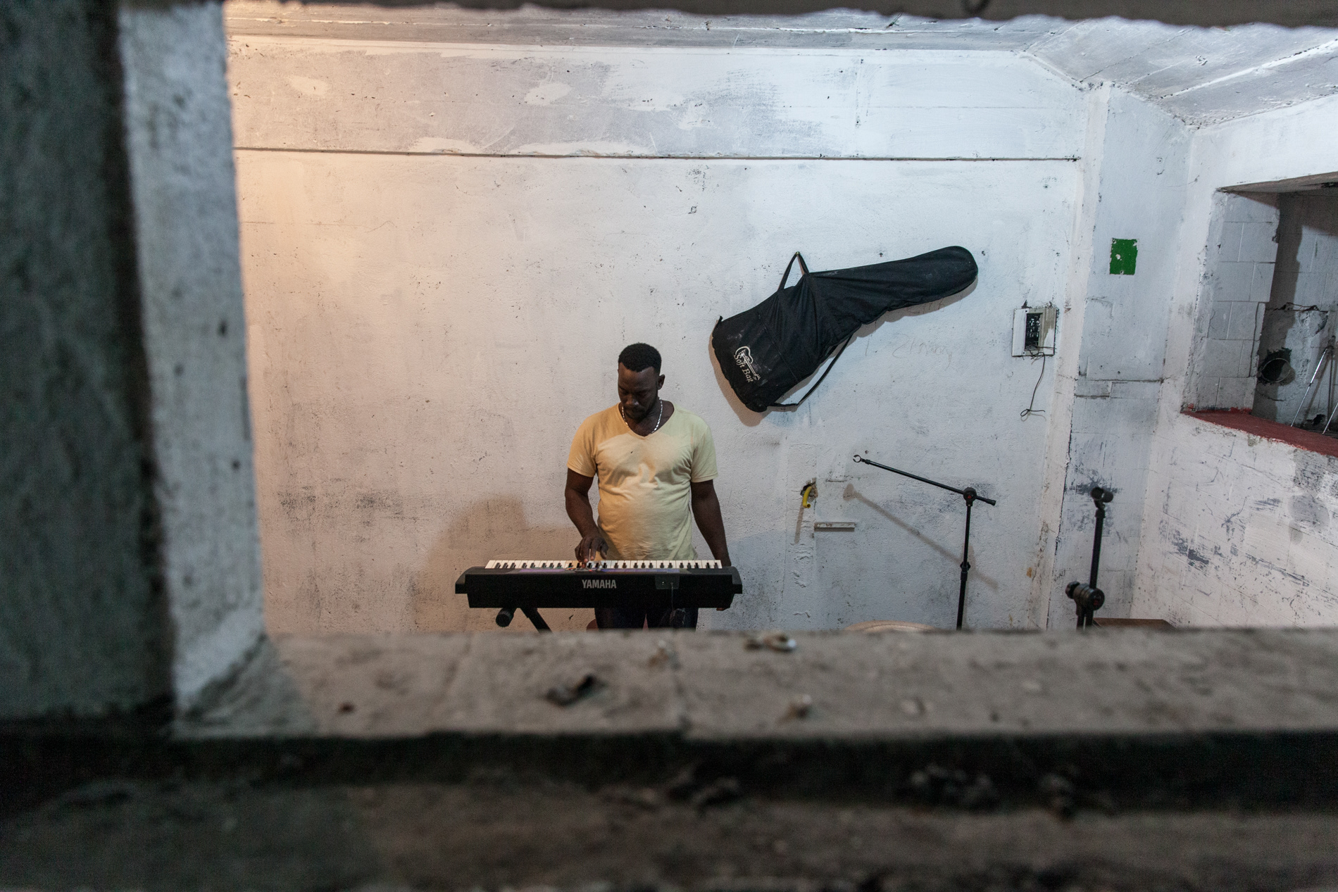 O haitiano Louides Charles pratica em um estúdio improvisado em uma ocupação no centro de São Paulo onde sua banda Satelite ensaia. Ele trabalha na construção civil no Brasil e fundou uma banda que toca músicas de seu país