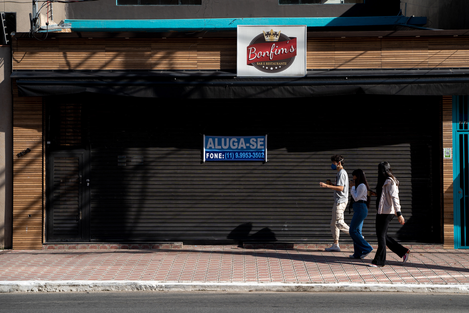 Pessoas passam por restaurante com placa de 'aluga-se' em São Paulo durante pandemia de Covid-19, em maio de 2020