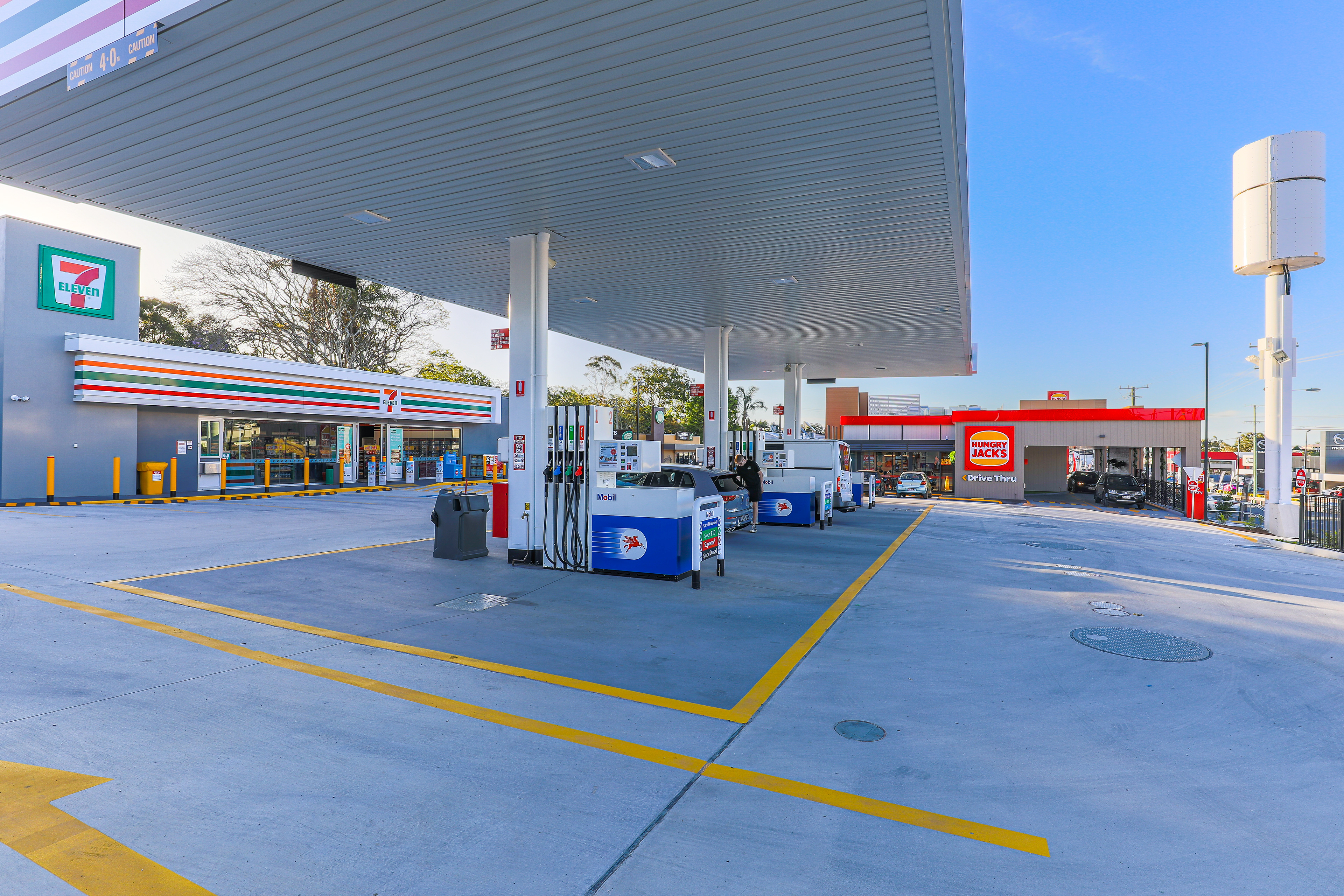 7-Eleven gas station with a drive-thru for Hungry Jack's, featuring modern amenities and vibrant signage, located in Brisbane, QLD. Professional commercial photography by Jeremy Murphy.